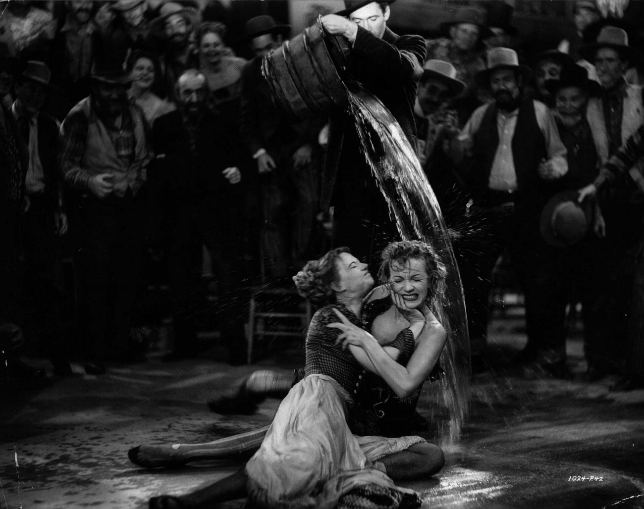 James Stewart Puts An End To A Fight Between Marlene Dietrich And Una Merkel By Pouring A Bucket Of Water Over Them, In A Scene From The Classic Western 'Destry Rides Again'