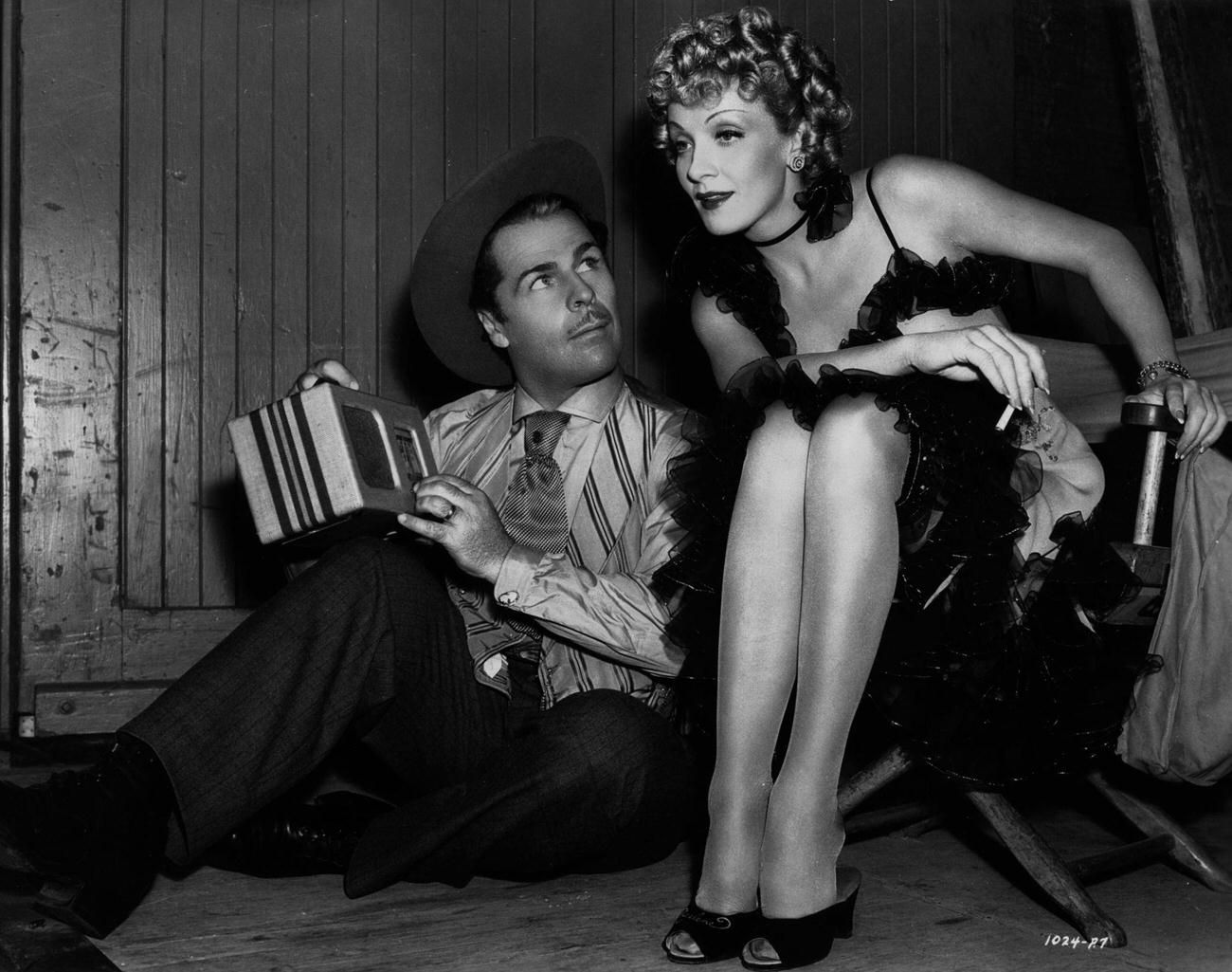 Marlene Dietrich And Brian Donlevy Listen To The Radio On The Set Of The Classic Western 'Destry Rides Again'.