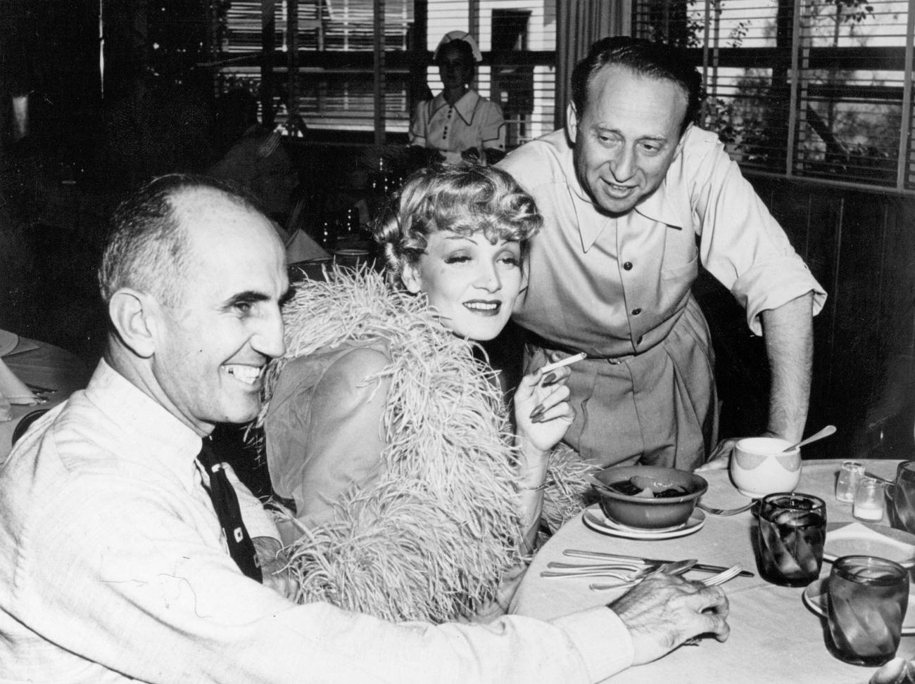 Marlene Dietrich Lunching With Director George Marshall (Left), And Producer Joe Pasternak On Her Latest Film 'Destry Rides Again'.