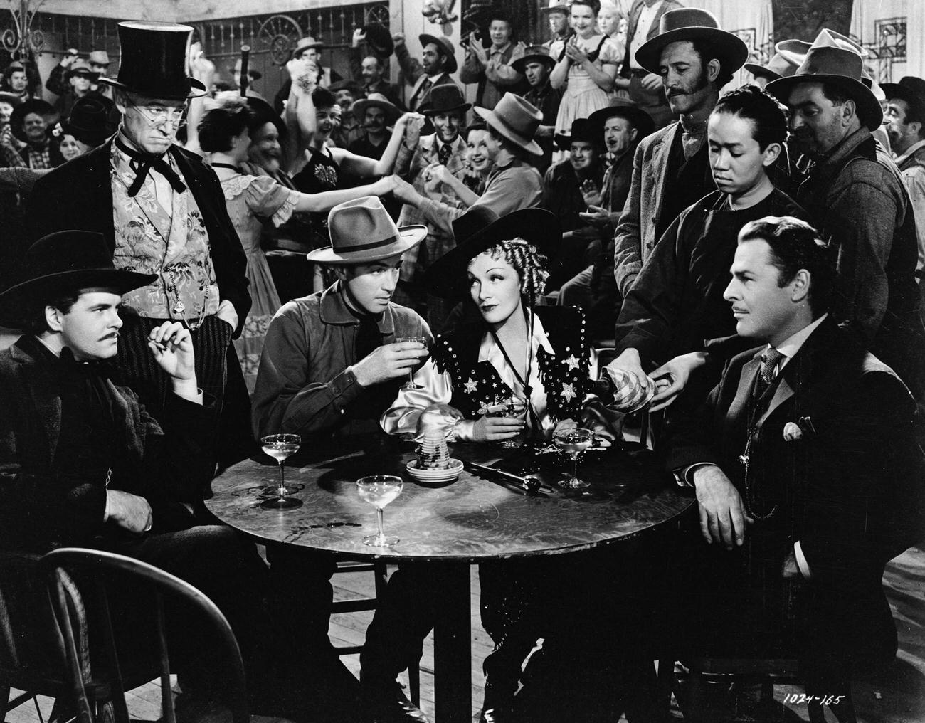 James Stewart And Marlene Dietrich Share A Drink With Brian Donlevy And Friends In A Scene From The Film 'Destry Rides Again'