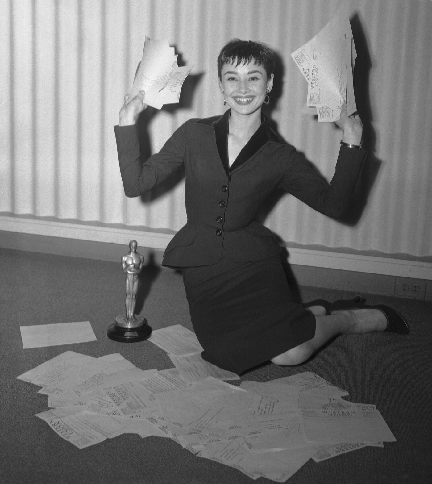 The Morning After...her Oscar Before Her, Audrey Hepburn Happily Waves Telegrams Congratulating Her On Winning The 1954 Motion Picture Academy Award For The Best Performance By An Actress.