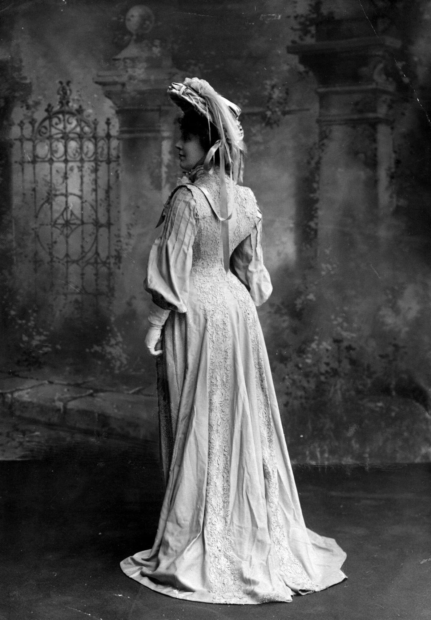 Miss Mansfield Wearing A Coatdress With Lace Detail And Full Sleeves, With A Feather Trimmed Hat.
