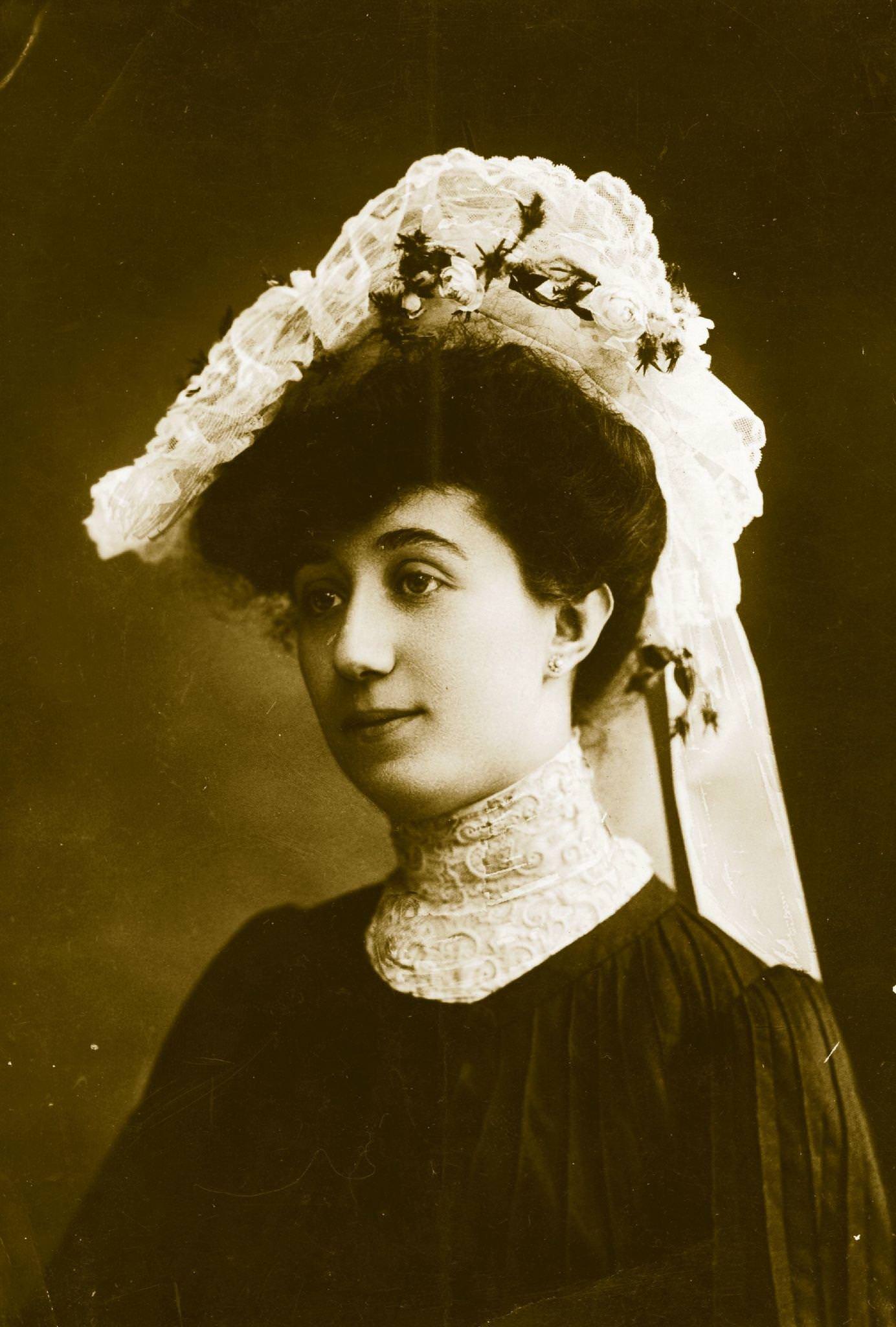 An Edwardian Lady Wearing A High Necked Blouse And Hat With Lace And Flower Trimmings.