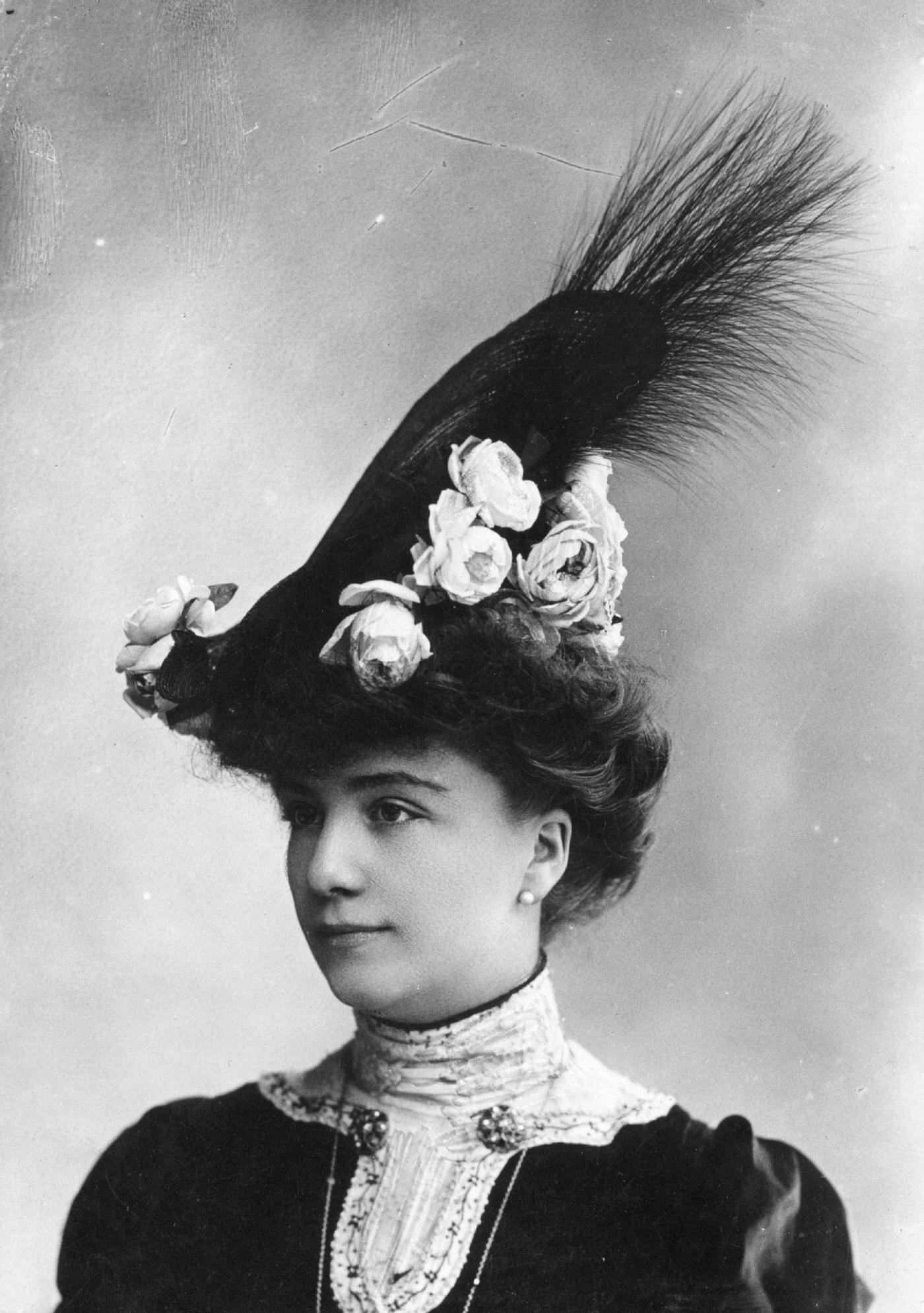 An Edwardian Woman Wearing A High Hat, Decorated With Flowers And Feathers, 1903