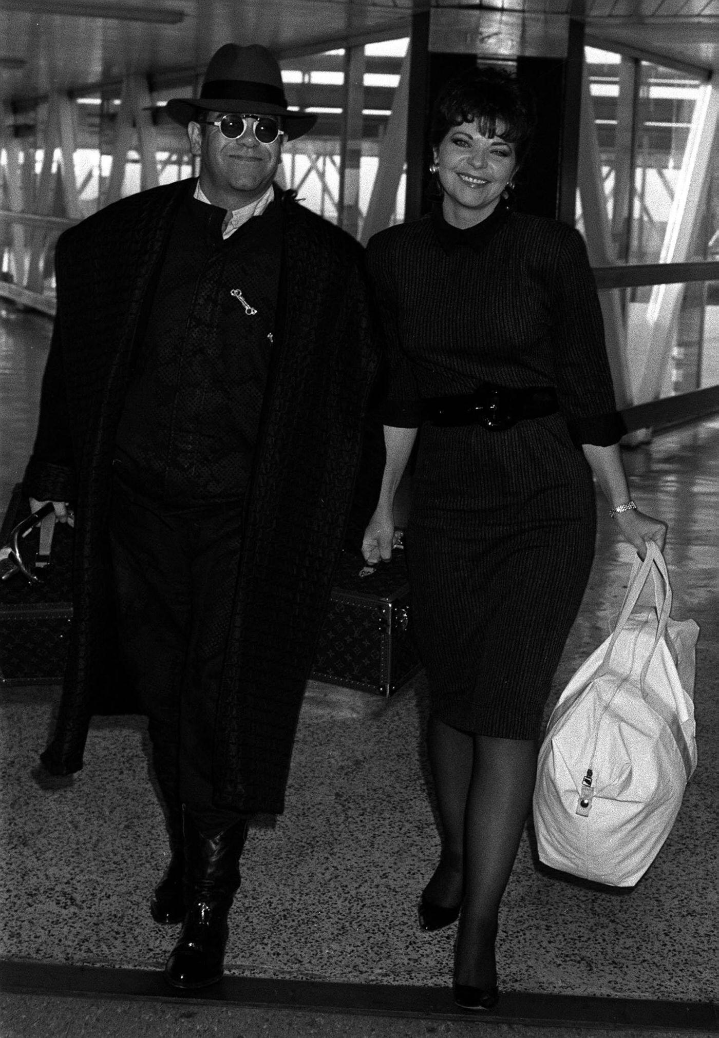 Elton John With Enate Blauel, Arrive At Heathrow Airport From Los Angeles. Elton Makes A Tv Appearance As Esther Rantzen'S Guest On The Wogan Show.