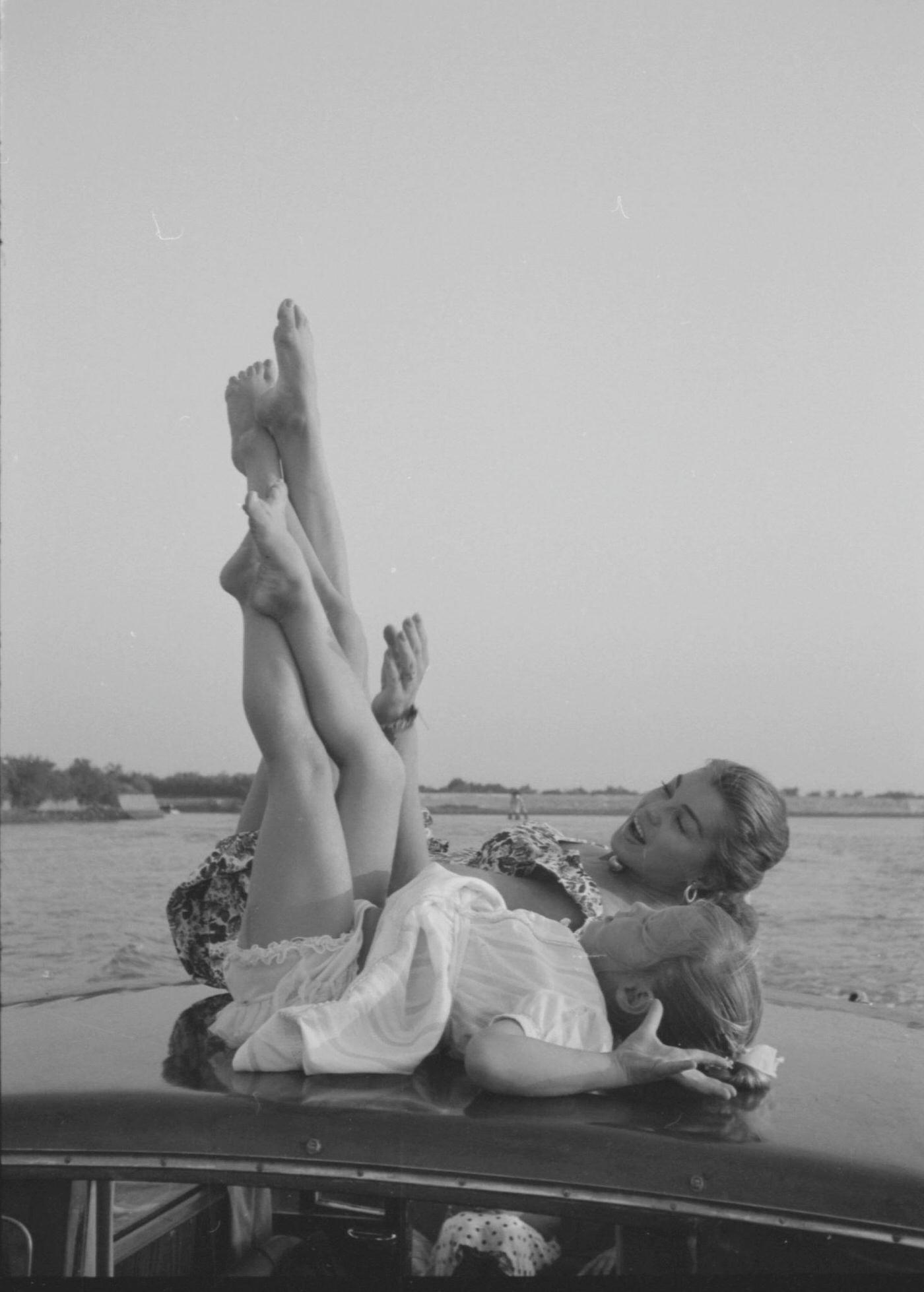 Esther Williams Lying On A Boat With A Little Girl, Raising Her Legs During The Xviii Venice International Film Festival. Venice, 1957