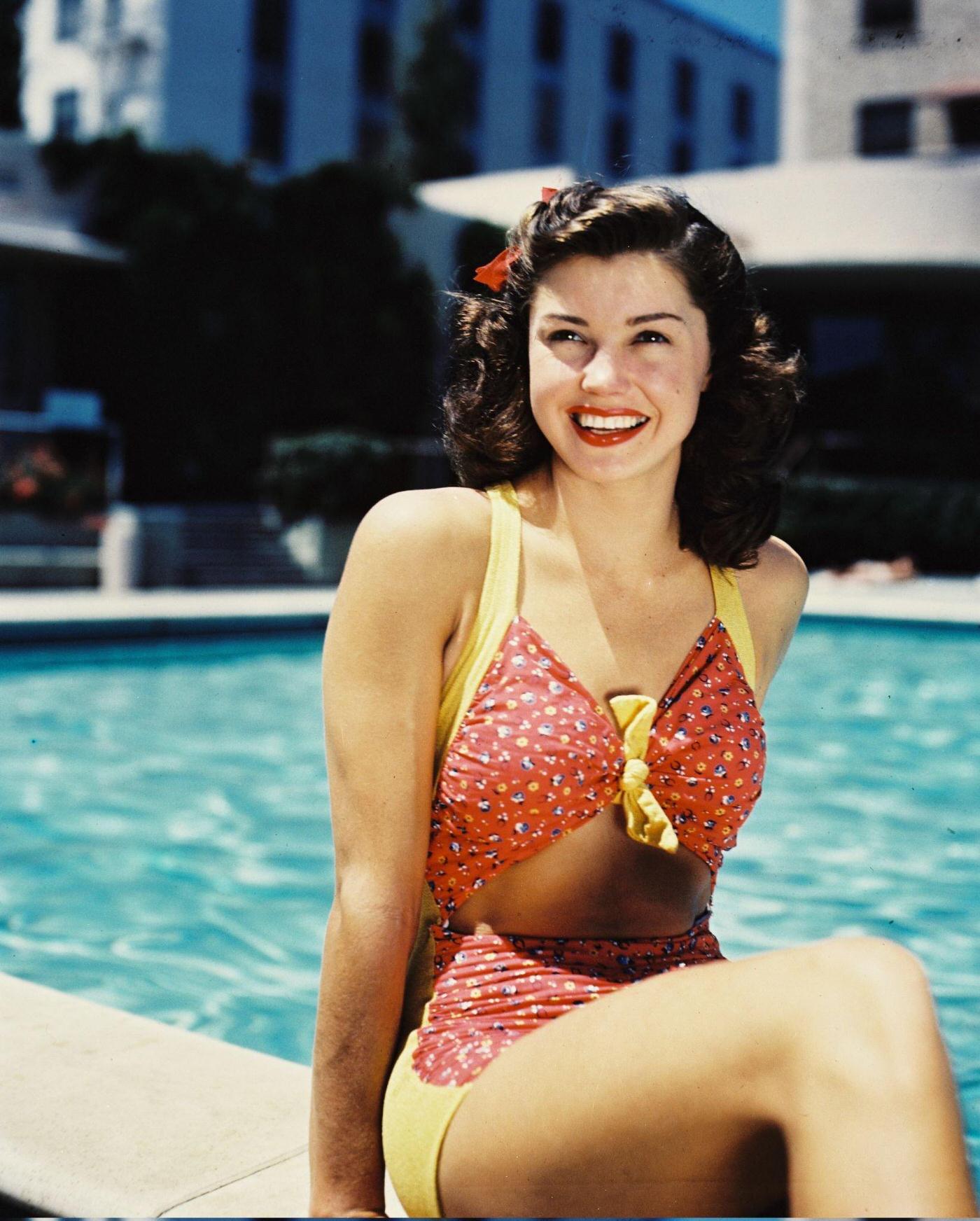 Esther Williams Wearing A Red-And-Yellow Bathing Costume, Smiling As She Poses At The Edge Of A Swmiming Pool, 1945