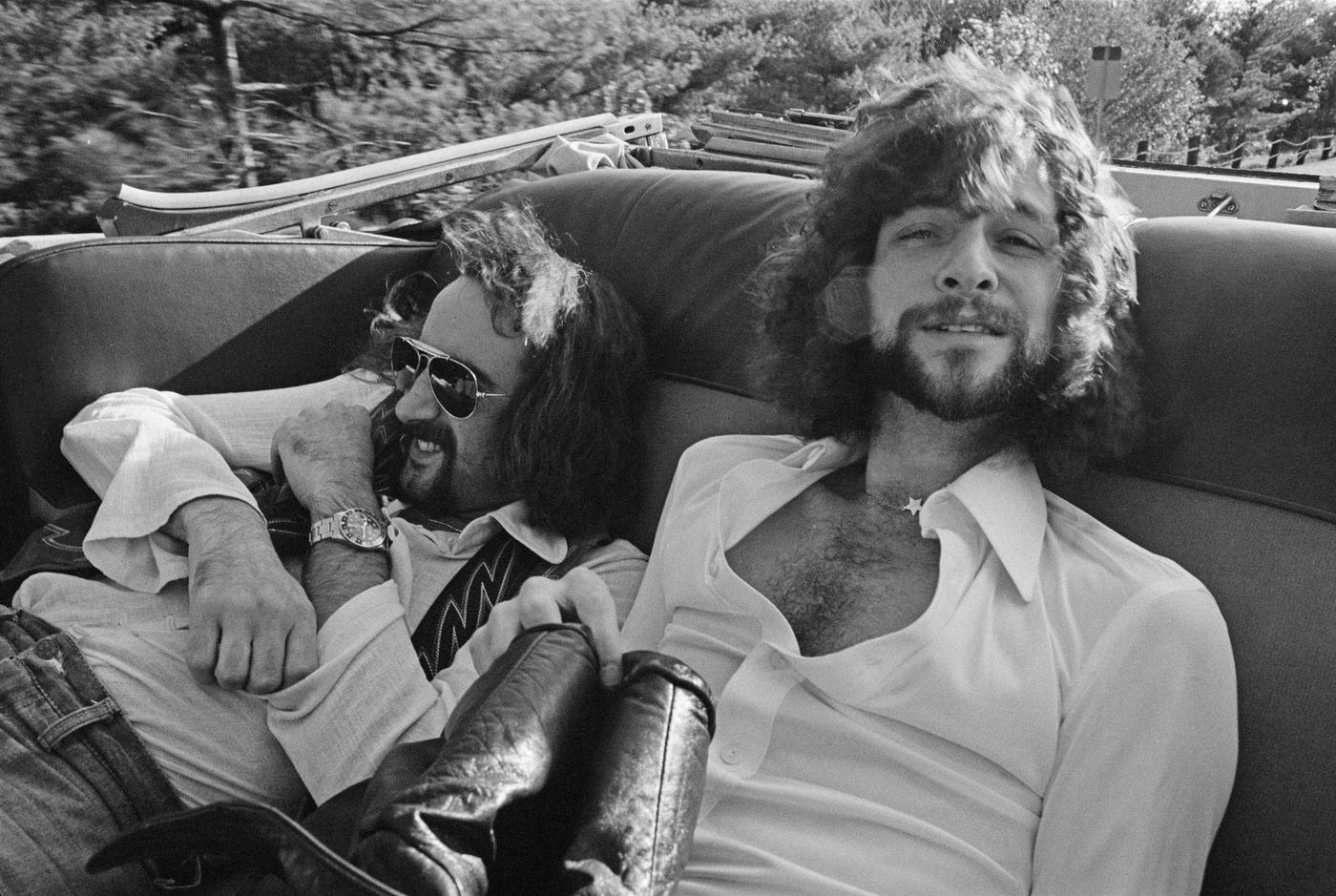 Bassist John Mcvie (Left) And Guitarist Lindsey Buckingham Of British-American Rock Band Fleetwood Mac Posed Sitting In A Vintage Car Outside A Recording Studio In New Haven, 1975