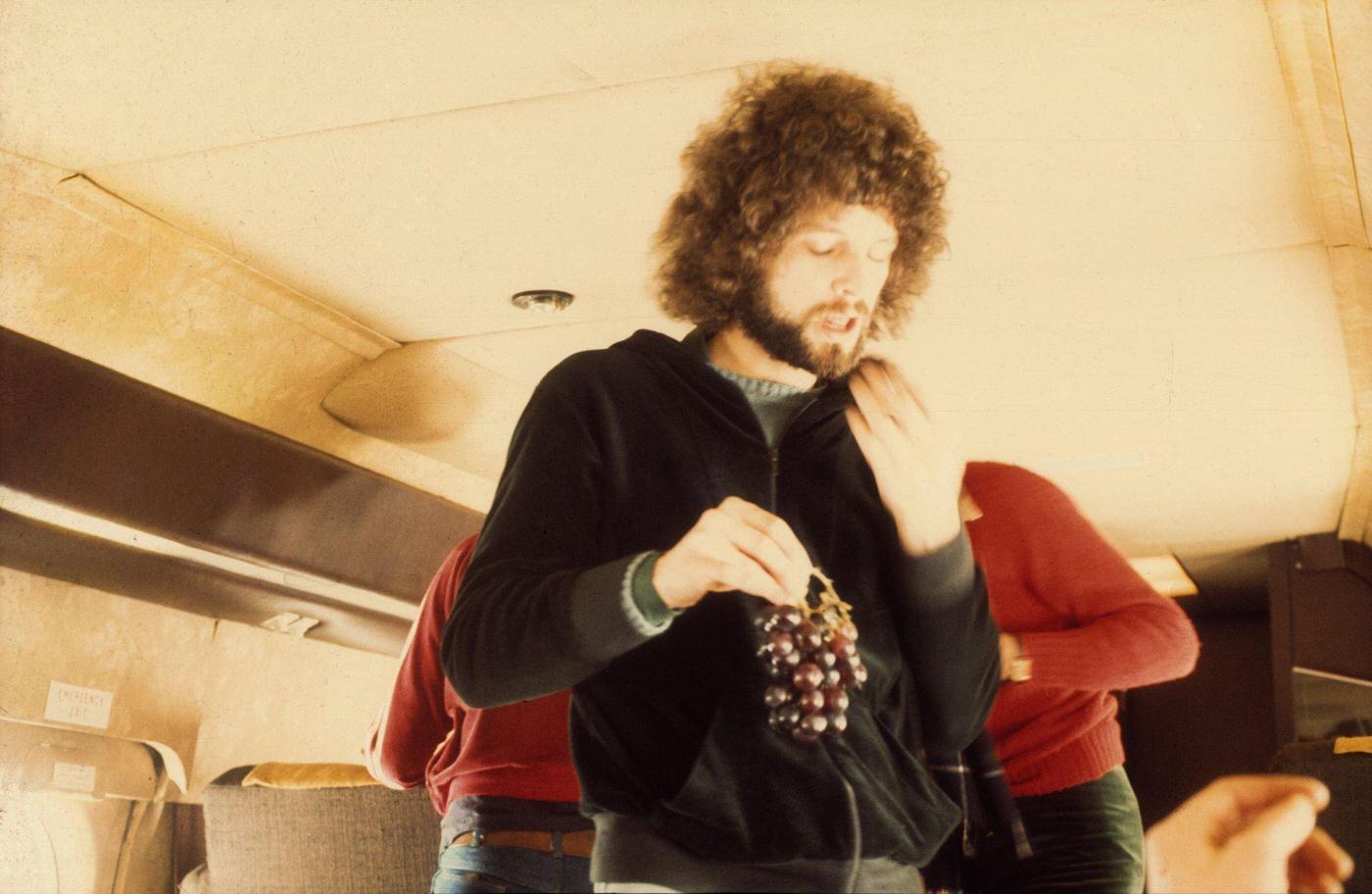 Guitarist Lindsey Buckingham Of The Rock Group 'Fleetwood Mac' Eats Grapes On Board Their Private Jet In 1975.
