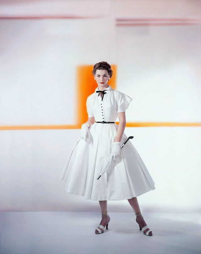 Georgia Hamilton Wearing A White Matelassé Cotton With Puffed Cupid Sleeves Below The Dropped Shoulder, A Black Bowtie, Jet Buttons And A Patent Belt, By Caroline Schnurer, Glamour, 1952