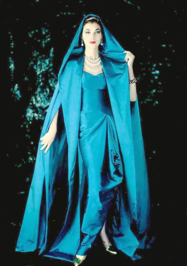 Rose Marie In Gorgeous Blue Draped Satin Gown Gathered At The Hip And Split At The Ankles Worn Under A Hooded Cloak Of Same Material By Grès, 1957