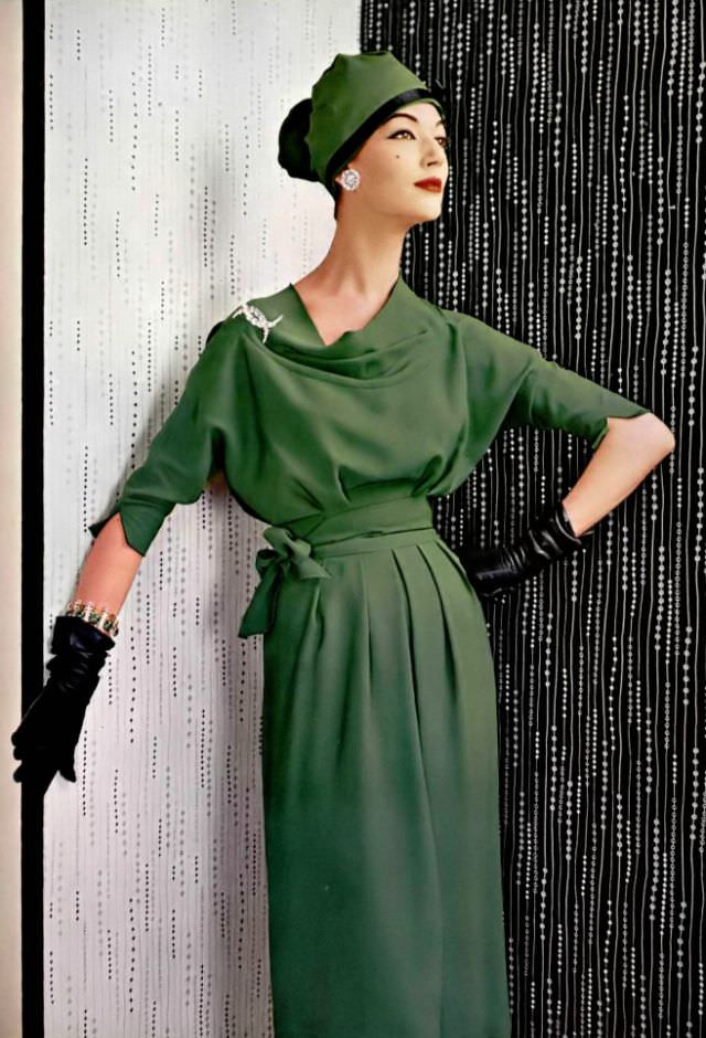 Simone D'Aillencourt In Green Crêpe Dress, The Supple Bodice With Cowl Neck Ends In Scalloped Sleeves, Belt Of The Same Material Is Tied In Knot At The Side, By Grès, Jewelry By Roger Scémama, 1957