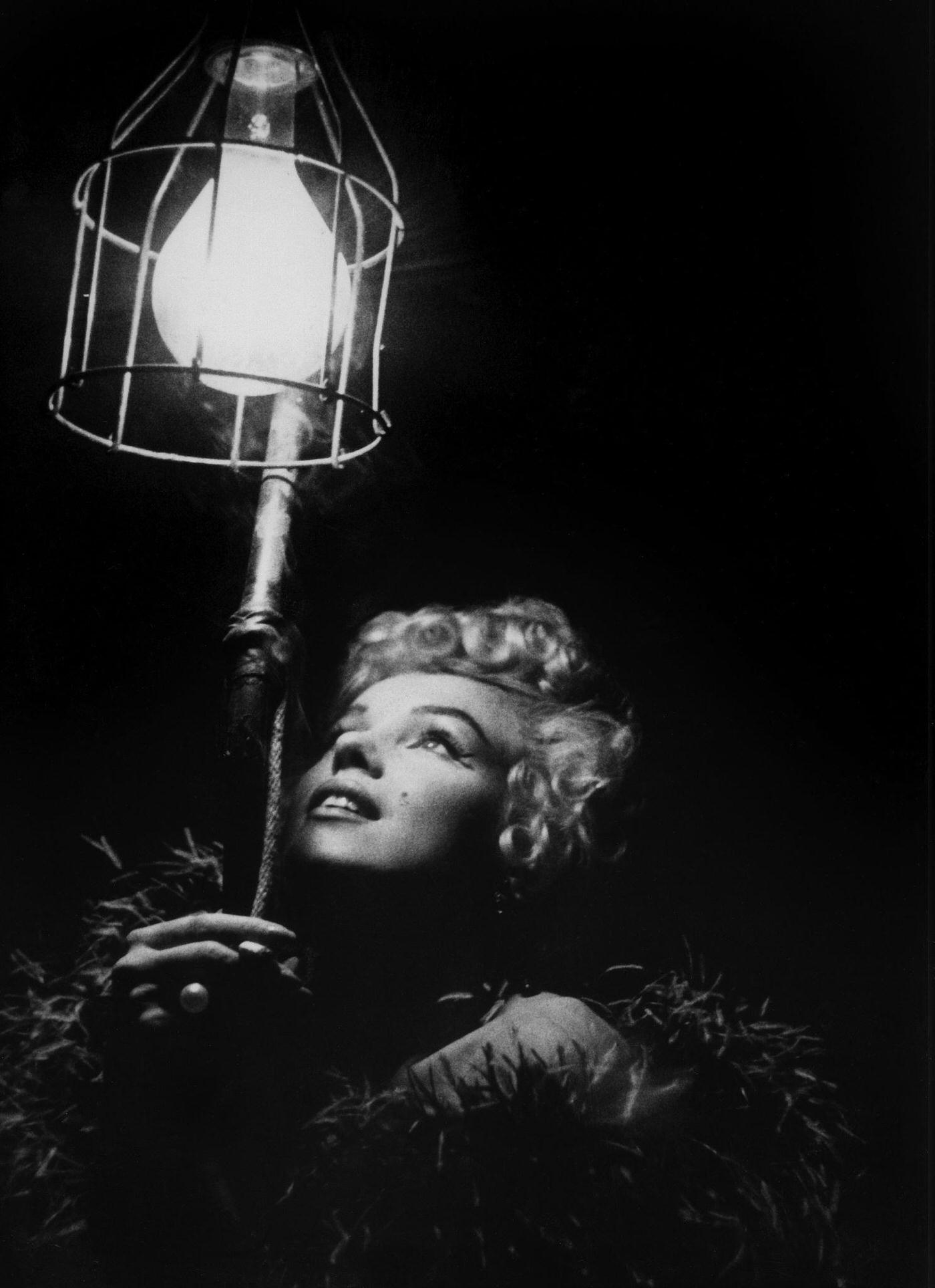 Marilyn Monroe Wearing A Feather Boa Looks Up Into A Bright Light In 1954 During The Filming Of &Amp;Quot;The Seven Year Itch&Amp;Quot;