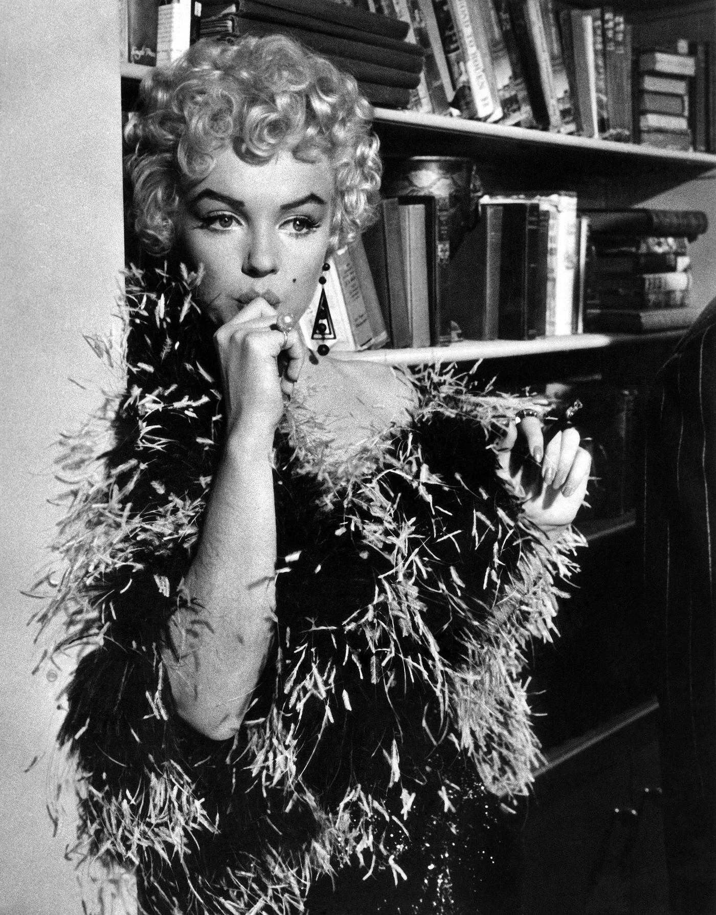 Marilyn Monroe Stands In Front Of A Bookcase Wearing A Feather Boa In 1954 During The Filming Of &Amp;Quot;The Seven Year Itch&Amp;Quot;