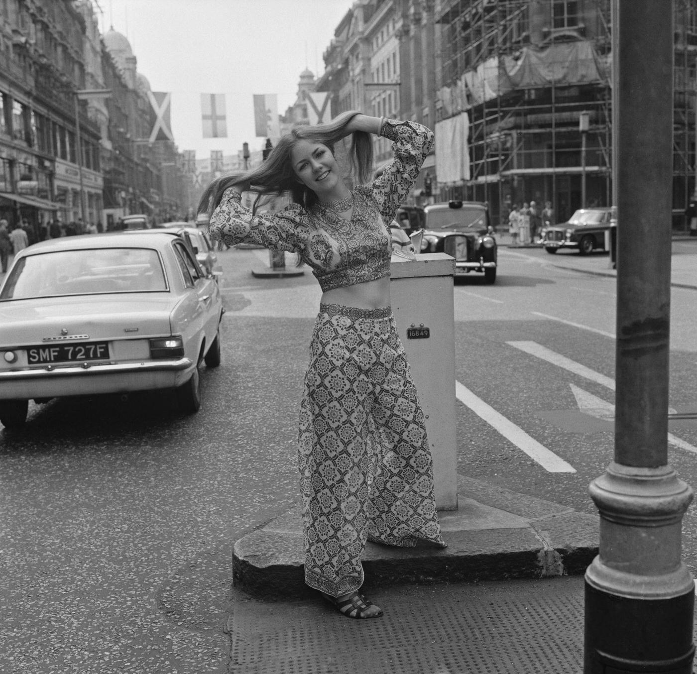 Female Fashion Model In Long Sleeves Crop Top And High-Waist Flared Pants In Bell Bottoms On Regent Street, London, 1970