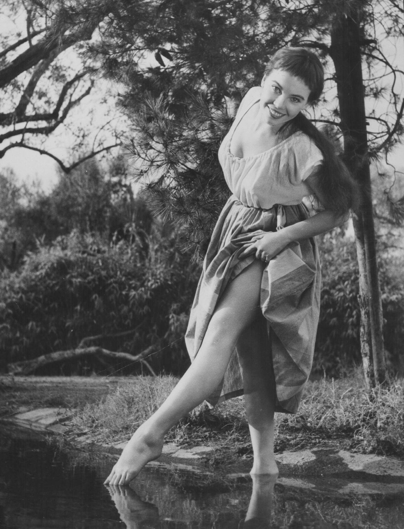 Leslie Caron Strikes A Dancer'S Pose By A Stream In Peasant Attire, 1954