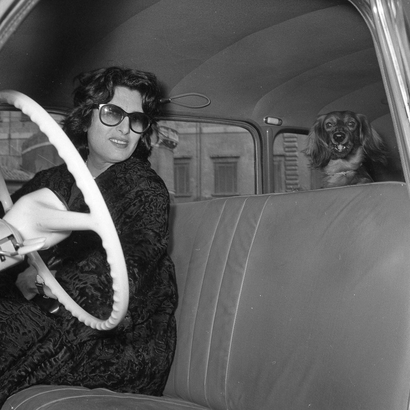 Italian Stage And Film Actress Anna Magnani Is Pictured With Her Dog In A Car In Rome, 1957
