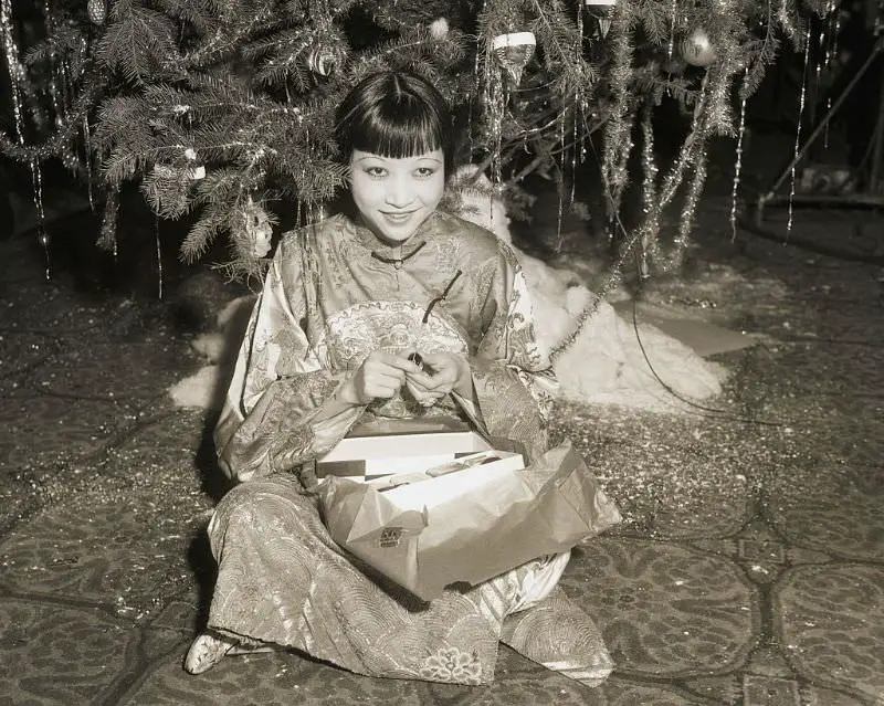 Anna May Wong Opens Present Under The Tree At A Christmas Celebration For Hollywood Stars At The Christy Hotel In 1932.