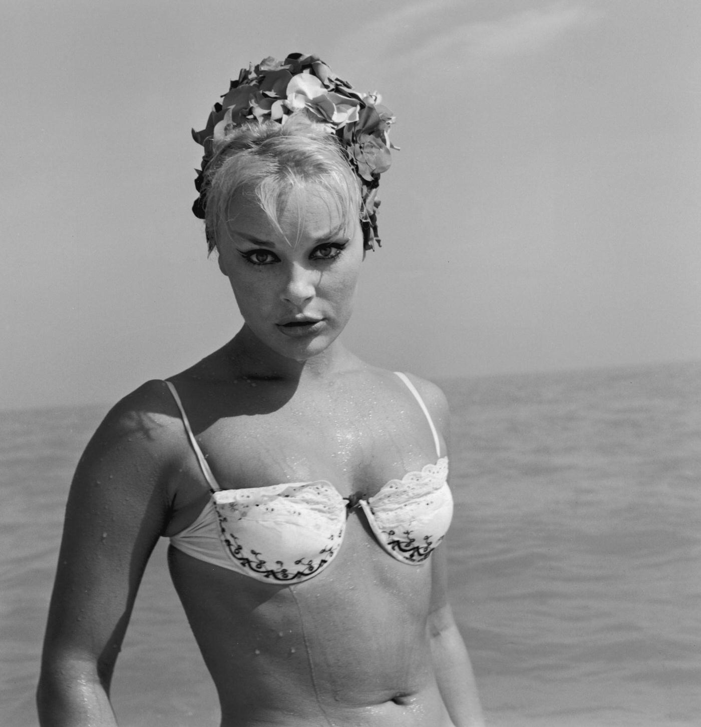 German-Born Actor Elke Sommer Poses On A Beach In A Bikini And Rose-Petal Bathing Cap After Taking A Swim, 1965.