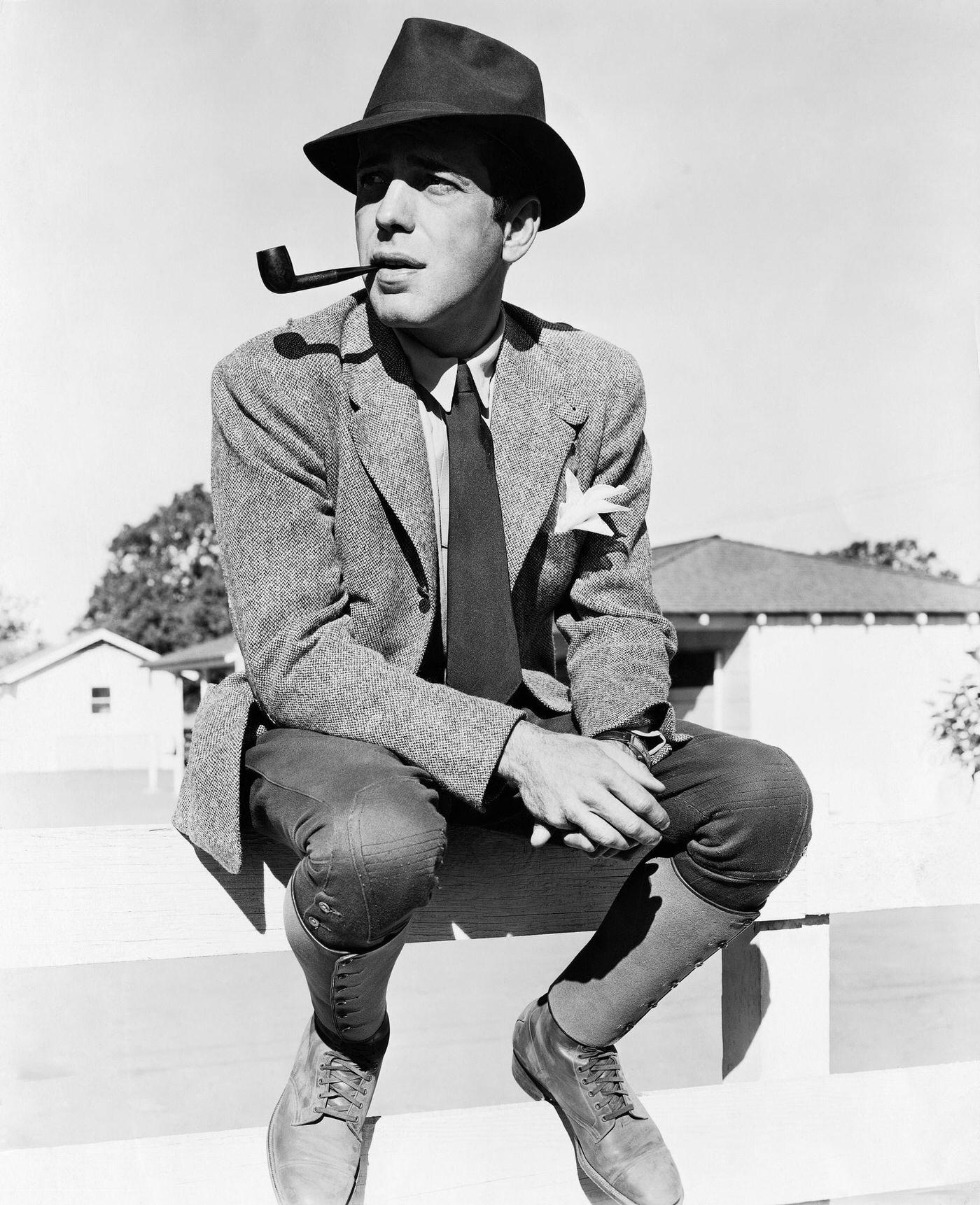 Humphrey Bogart Sitting On A Fence With A Pipe