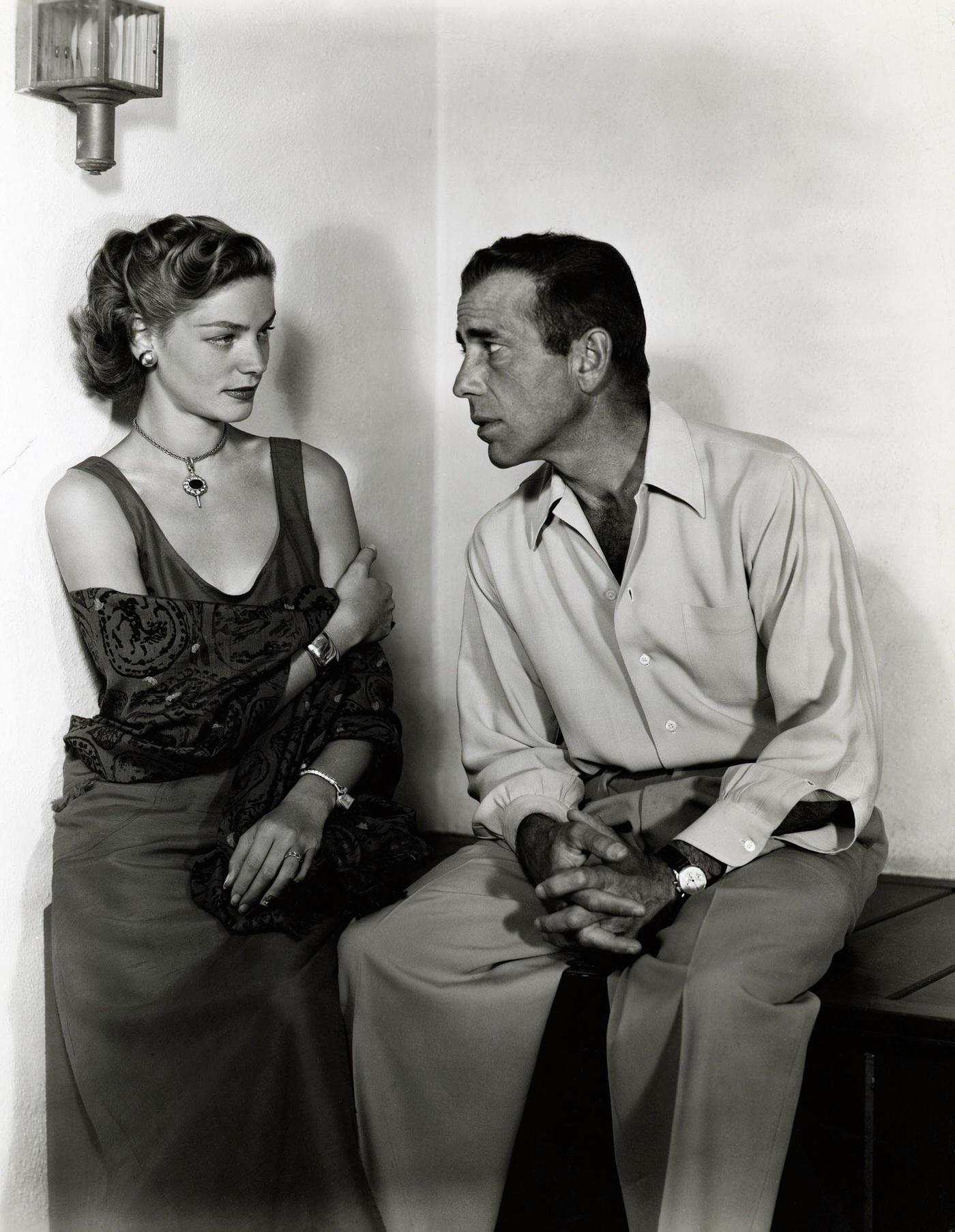Humphrey Bogart With Lauren Bacall Seated In Evening Gown And Silk Shirt And Pants, Ca. 1940-1957