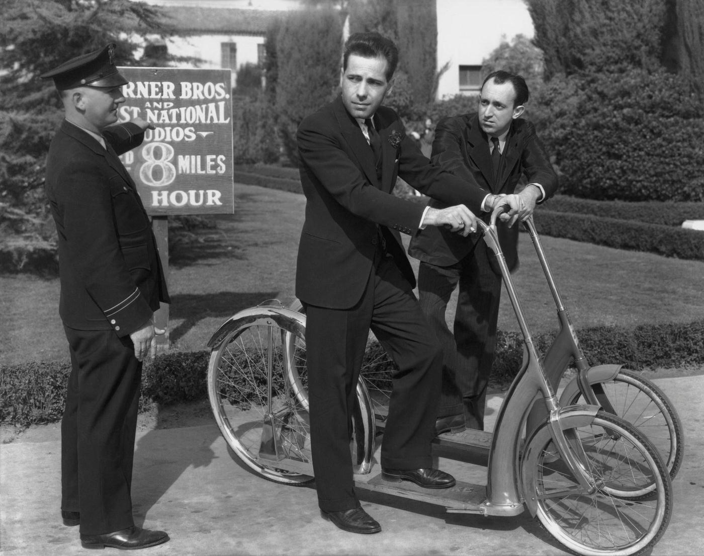 American Actors Humphrey Bogart (1899 Ð 1957) And Allen Jenkins (1900 Ð 1974) Are Stopped For Speeding On Their Scooters By A Security Guard At The Warner Bros. Studios 1938.