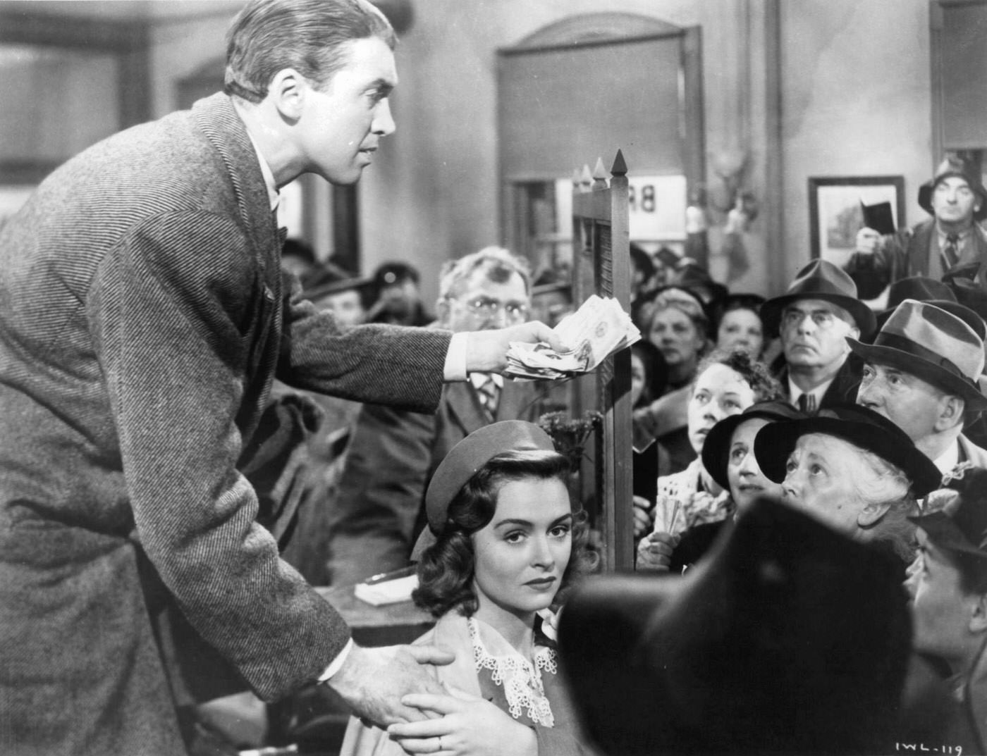 James Stewart Holding Donna Reed'S Hand While Talking With Others In 'It'S A Wonderful Life', 1946.