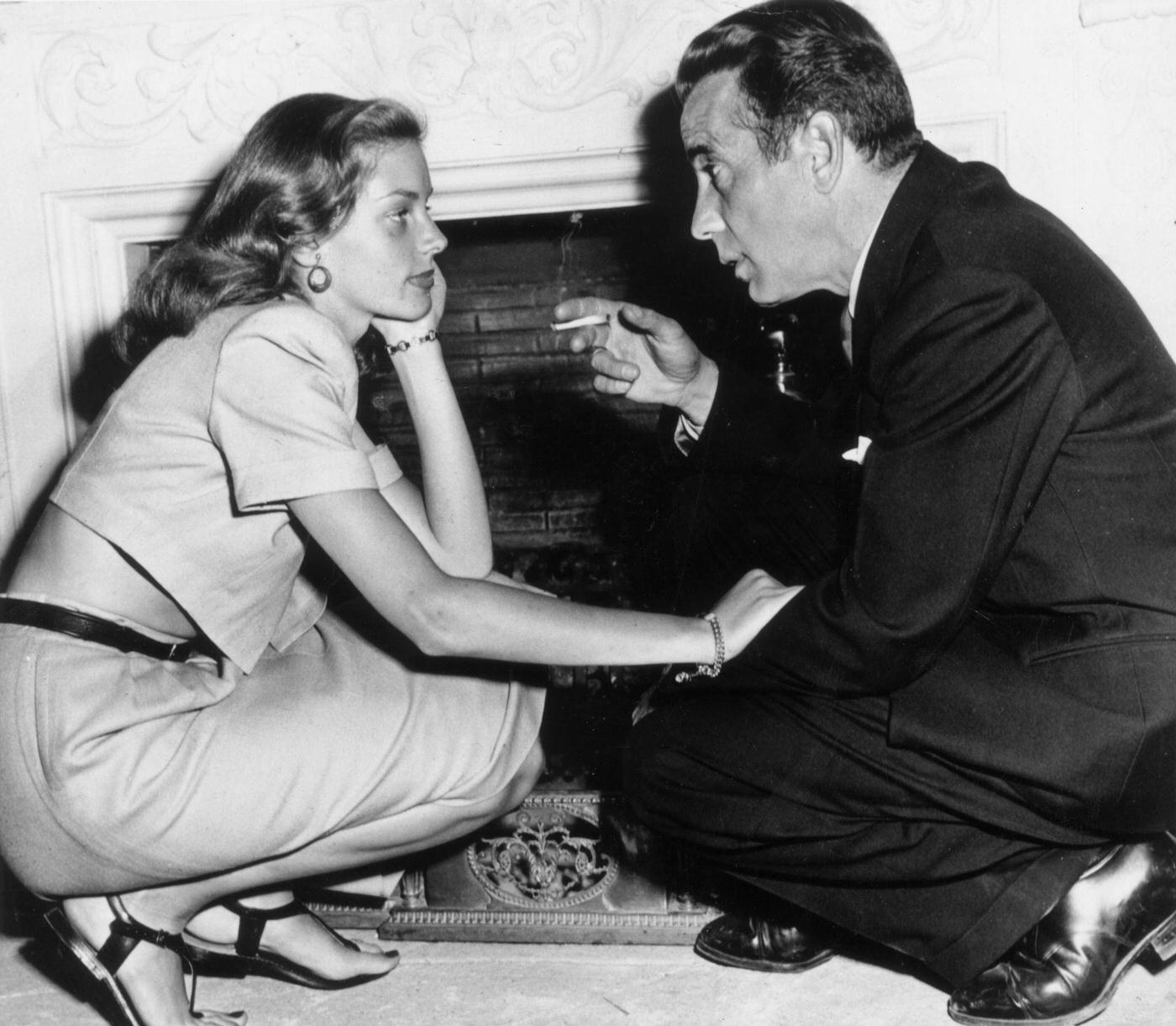 Married American Actors Lauren Bacall And Humphrey Bogart Kneel In Front Of A Fireplace In Their Home, California, 1945
