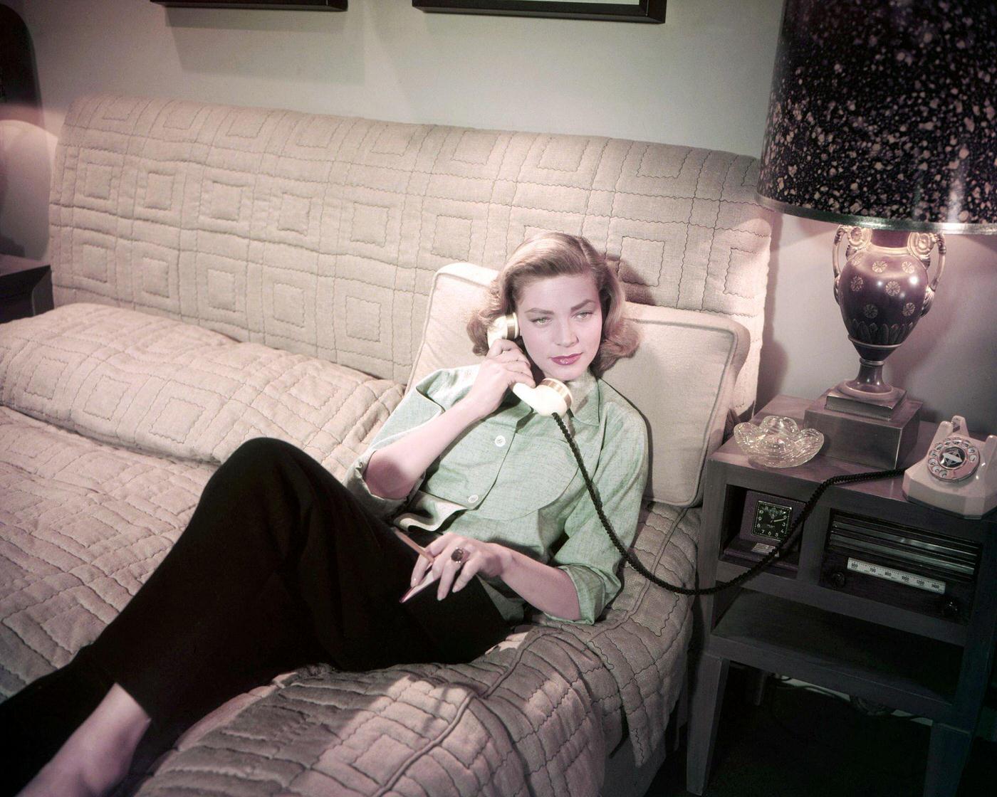 Lauren Bacall Lying On A Bed And Making A Telephone Call In 1955.