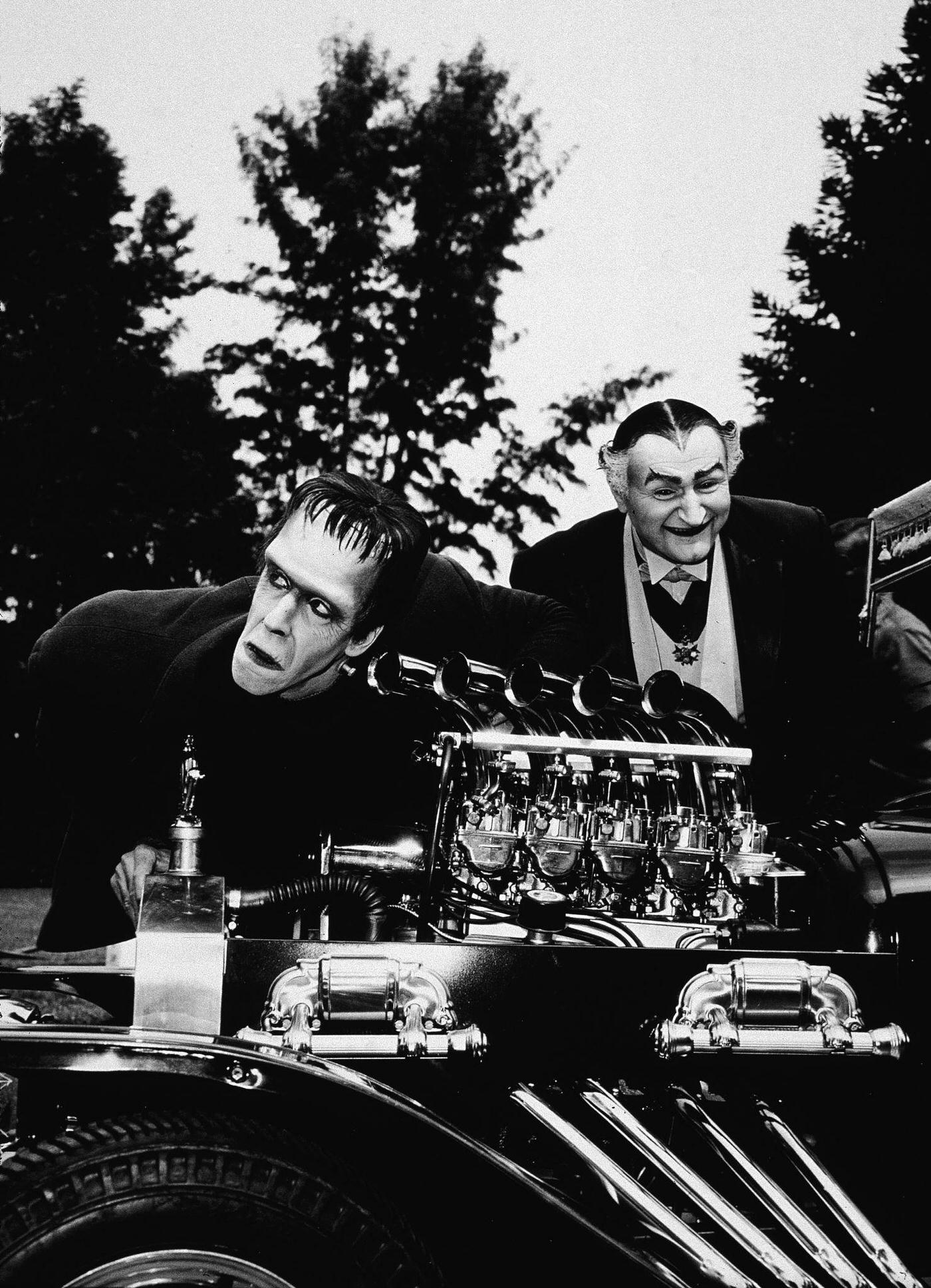 Fred Gwynne And Al Lewis Examine A Dragster Car Engine In A Scene From 'The Munsters,' 1964.
