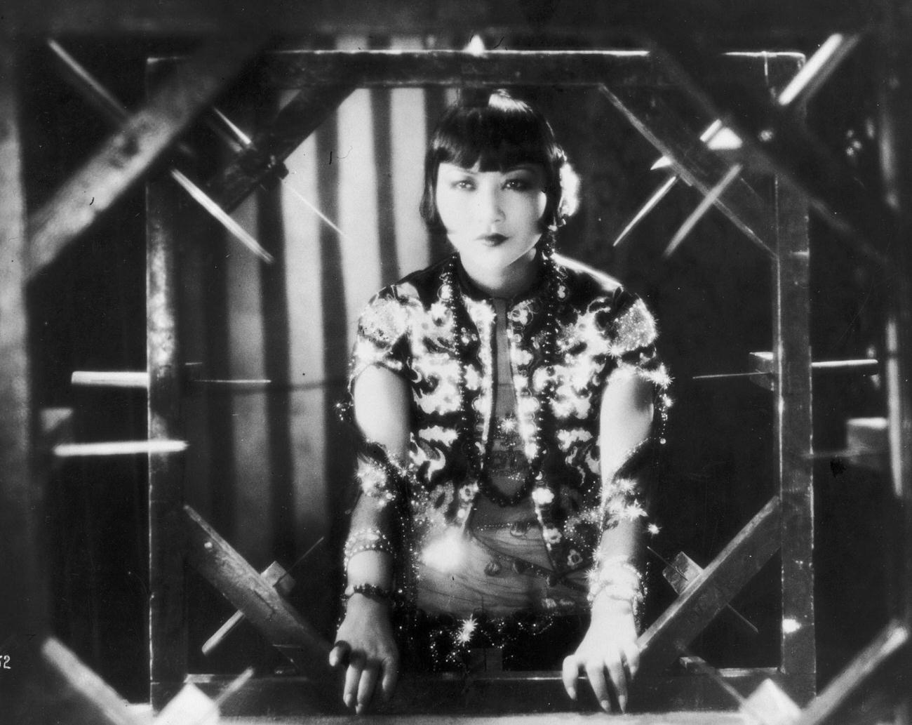 Anna May Wong Framed By A Sinister-Looking Contraption In A Film Still, Circa 1935.