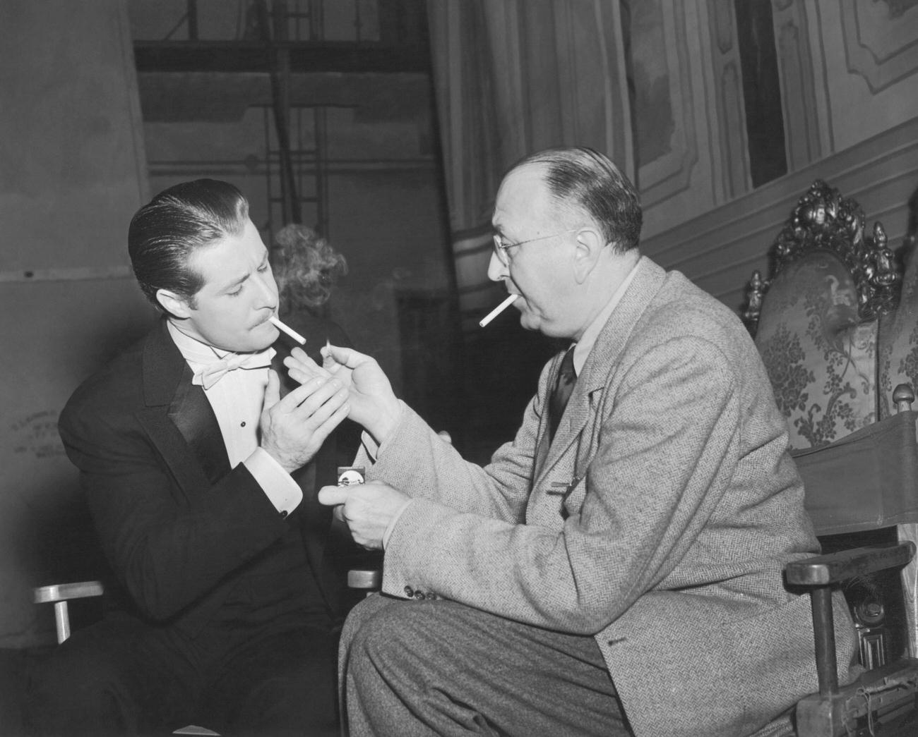 Director Irving Cummings Holds A Match For Don Ameche On The Set Of 'Down Argentine Way', March 17, 1940.