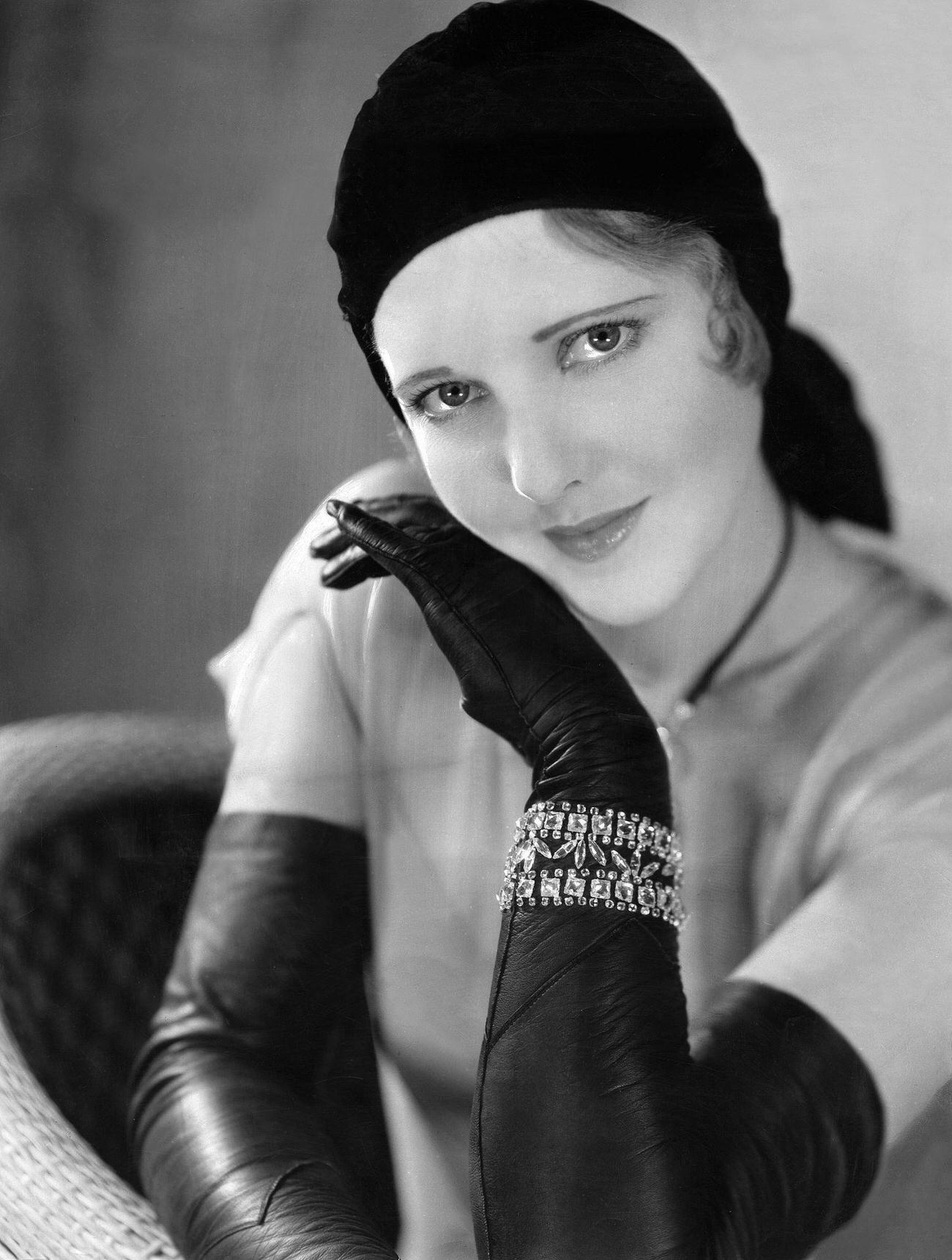 Jean Arthur Wearing A Hat, Long Black Leather Gloves, And Arm Jewelry, Circa 1930.