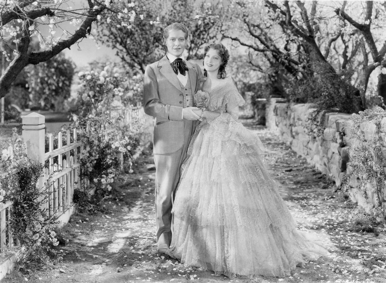 Nelson Eddy And Jeanette Macdonald Stand Arm In Arm, Hand In Hand In A Garden In 'Maytime,' 1937.