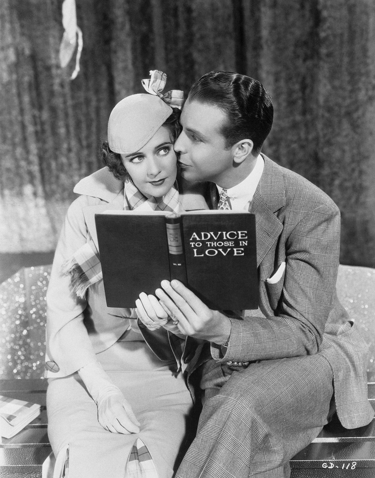 Ruby Keeler And Dick Powell Embracing With A Book.