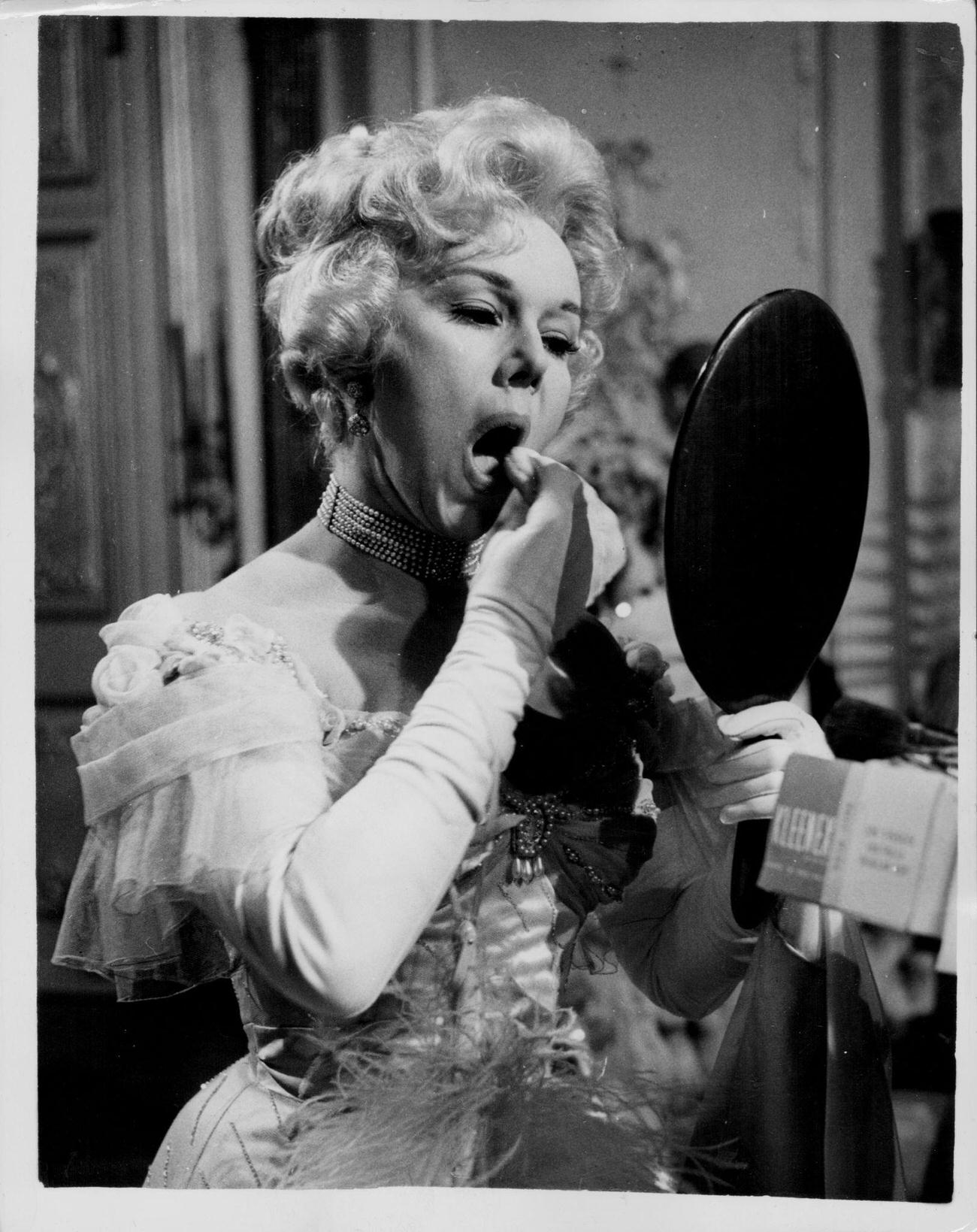 Eva Gabor Applying Makeup On The Set Of 'The Truth About Women', 1957.