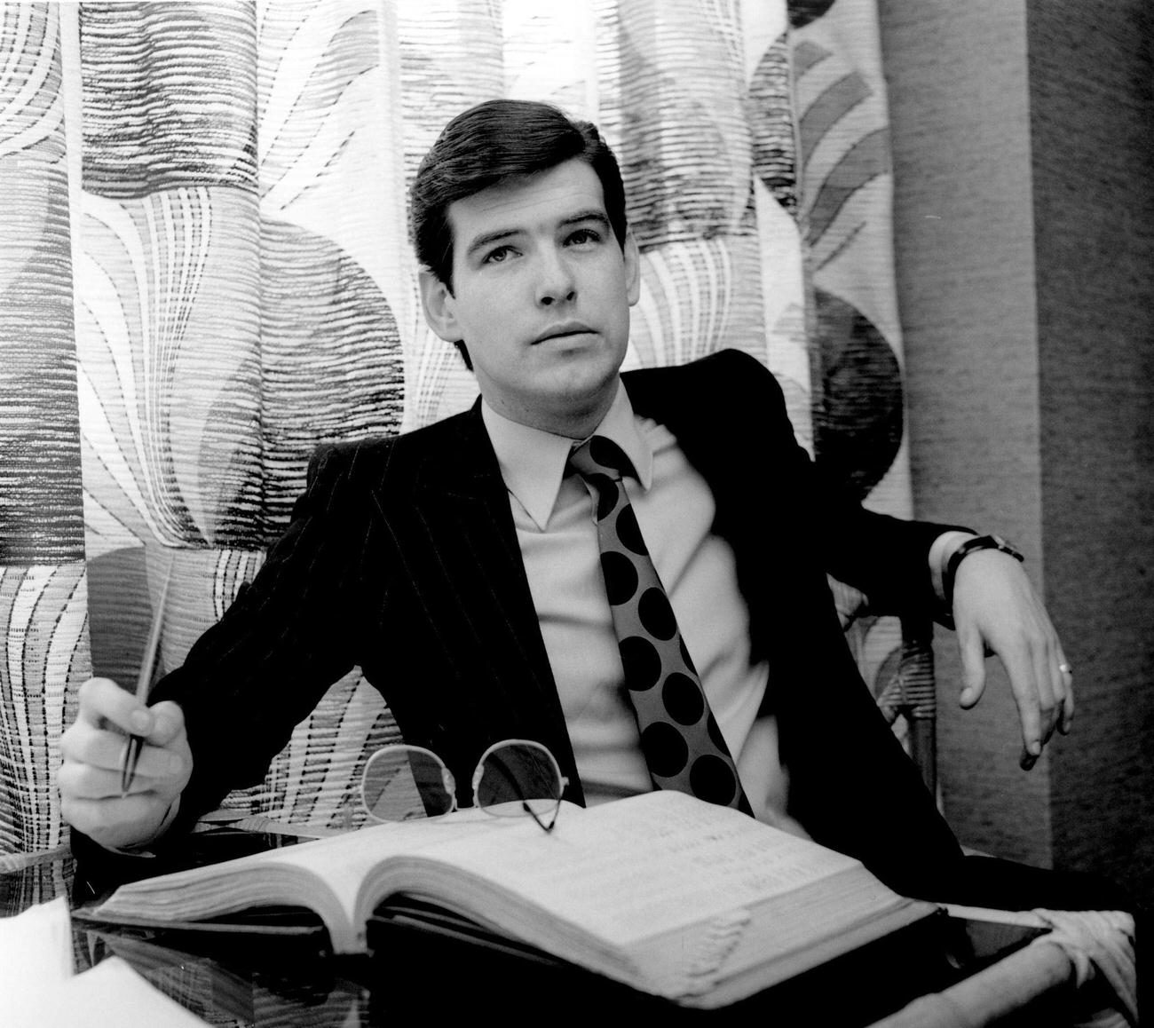 Pierce Brosnan Behind An Office Desk In A Suit And Tie, London, Circa 1978.