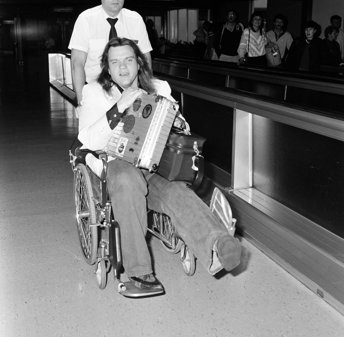 Meat Loaf Leaving Heathrow Airport In A Wheelchair, 1985.