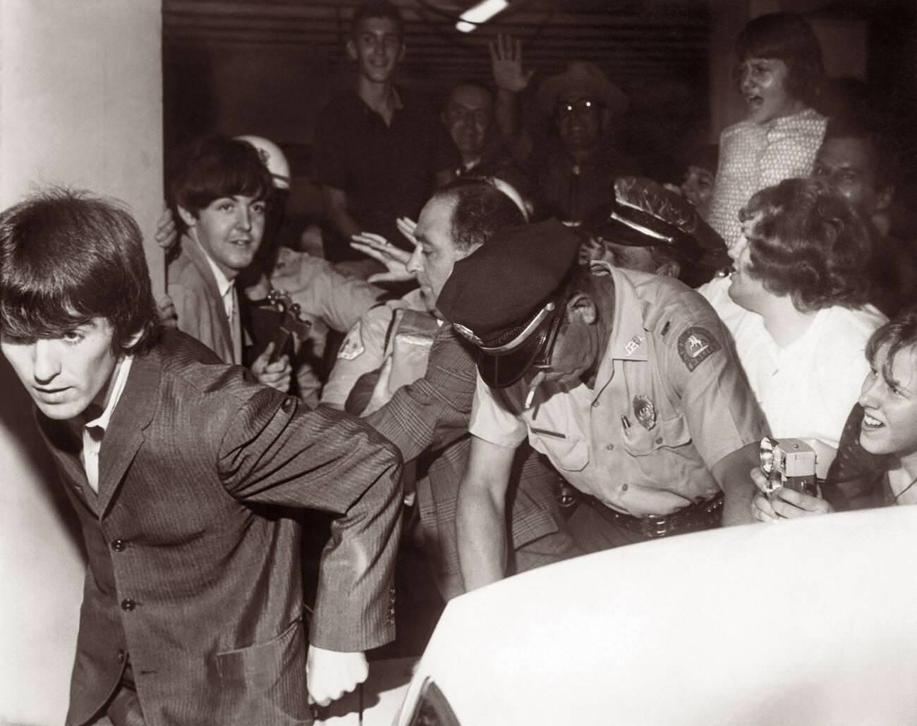 The Beatles (George Harrison In The Foreground And Paul Mccartney Behind Him) Leaving The George Washington Hotel With Police Trying To Control The Pressing Fans As The Band Headed For Their Gator Bowl Concert In Jacksonville, Florida, 1964.