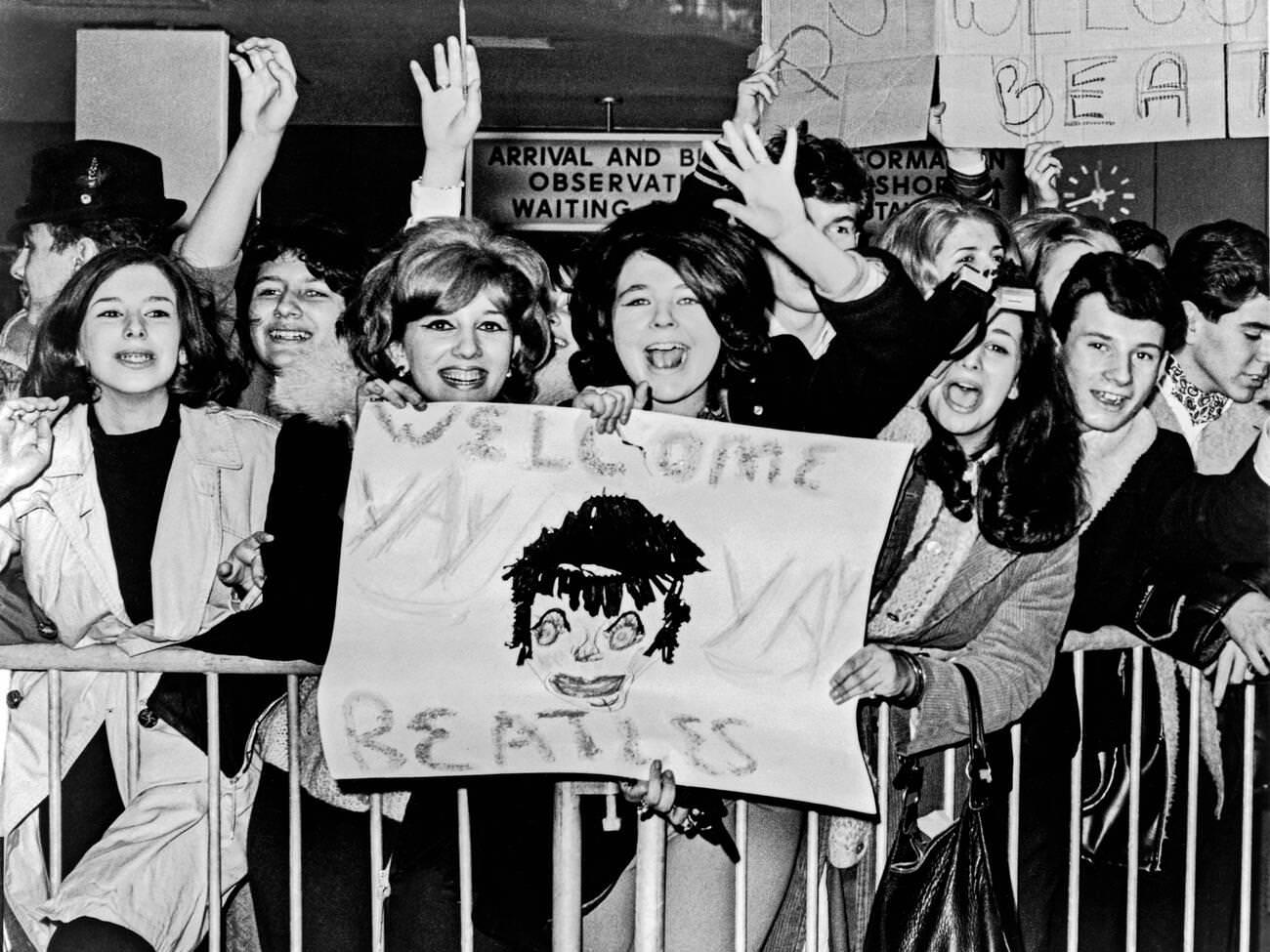 Screaming Teenagers Wave A Crude Sign As They Welcome The Beatles Upon Their Arrival At New York'S John F. Kennedy Airport, 1964.