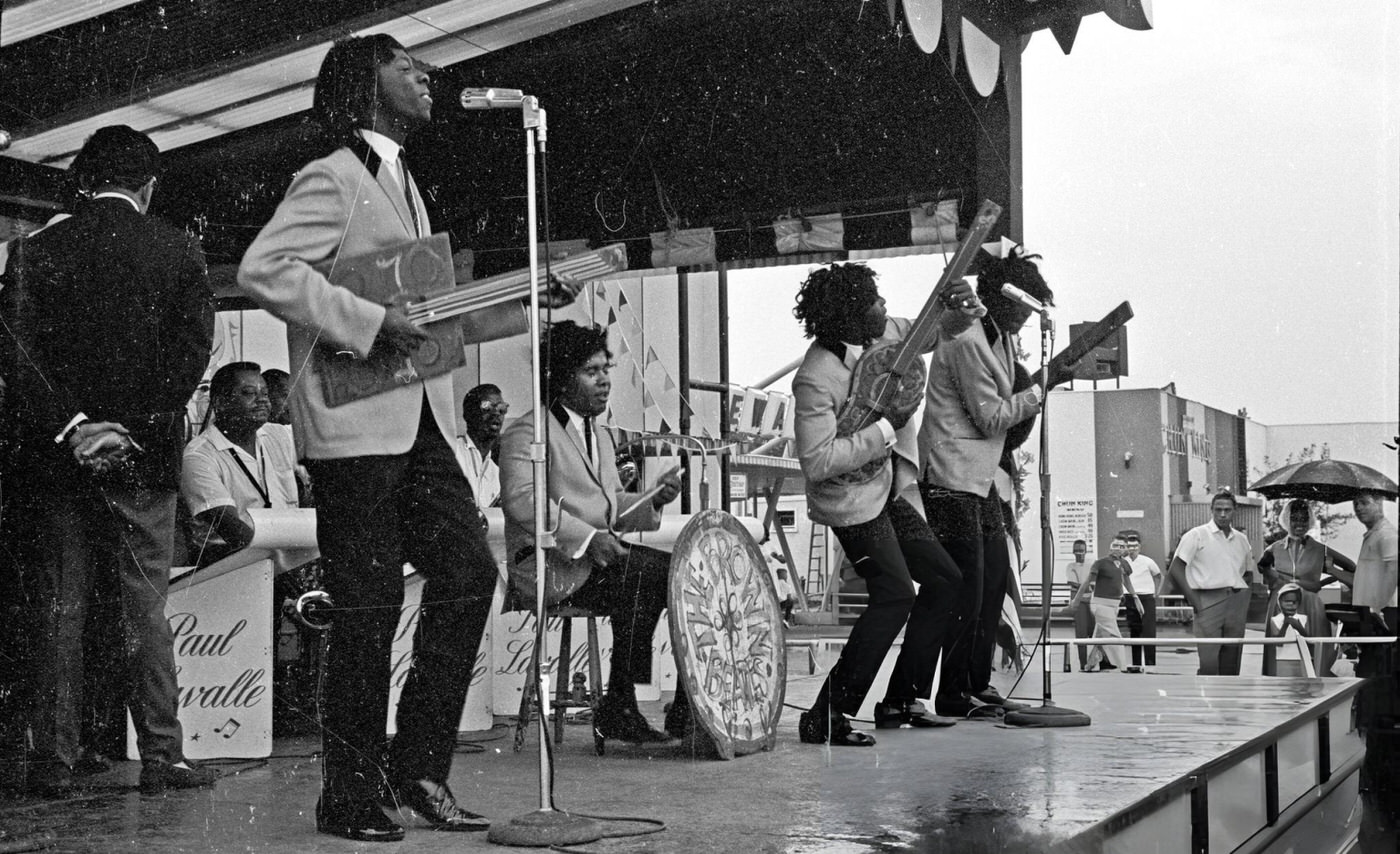 R&Amp;Amp;B Vocal Group &Amp;Quot;The Spinners&Amp;Quot;, Which Included Bobbie Smith, Edgar &Amp;Quot;Chico&Amp;Quot; Edwards, Billy Henderson, Henry Fambrough, And Pervis Jackson, Perform &Amp;Quot;The Beatles'&Amp;Quot; Song &Amp;Quot;I Saw Her Standing There&Amp;Quot; Wearing Wigs And Using Prop Guitars In Costume As &Amp;Quot;The Brown Beatles&Amp;Quot; At Freedomland Amusement Park, Bronx, New York, 1964.