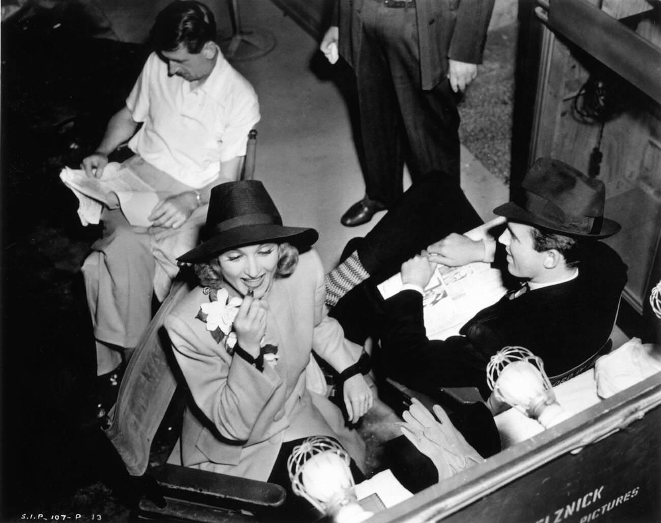 Director John Cromwell Studies The Script While Carole Lombard Retouches Her Lips, 1939.