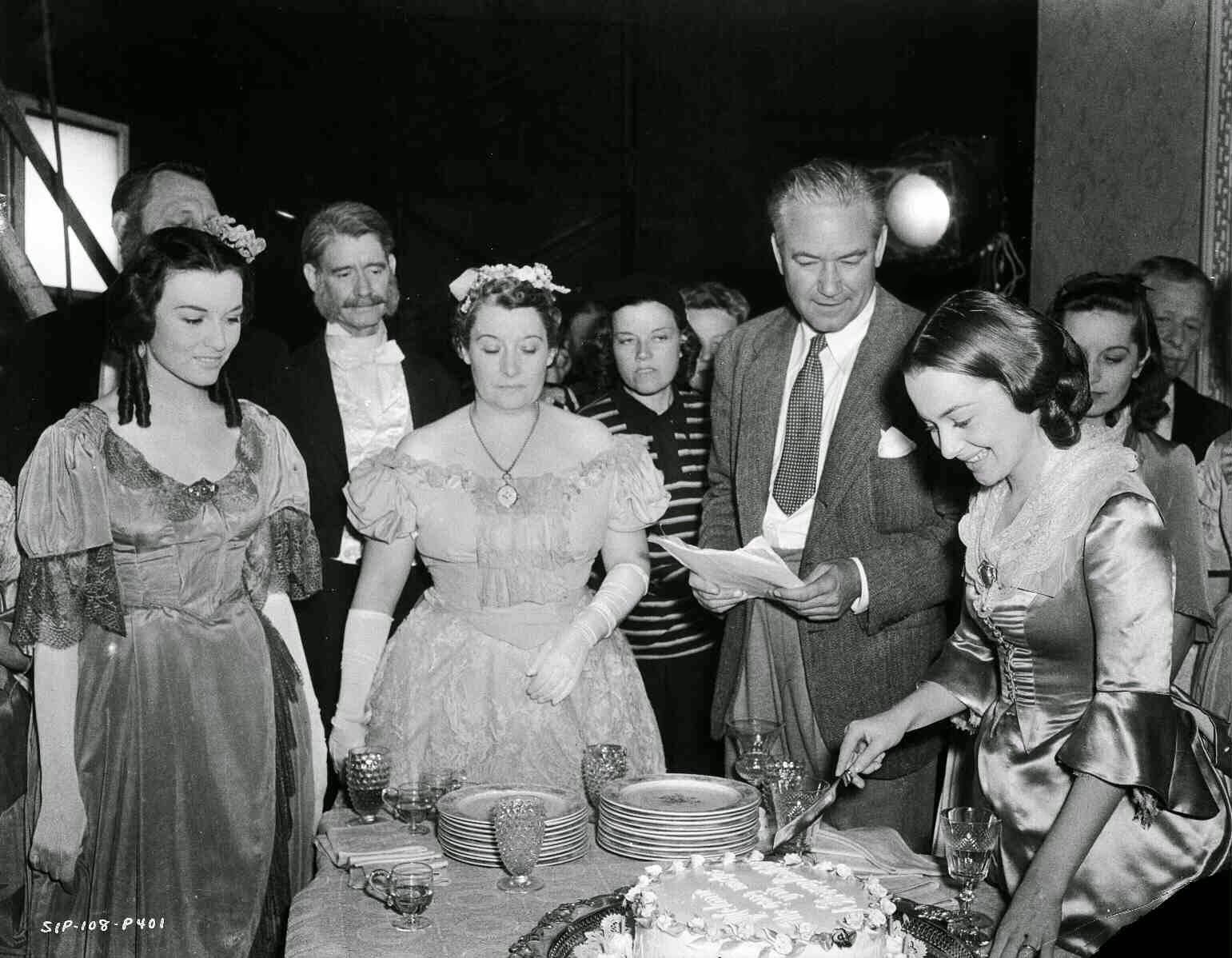 Cast And Crew Celebrating The Birthday Of Olivia De Havilland As Melanie Hamilton, Who Is Cutting Cake. Director Victor Fleming, Script Girl Lydia Schiller (In Striped Shirt), And Unknown Others Are Present.