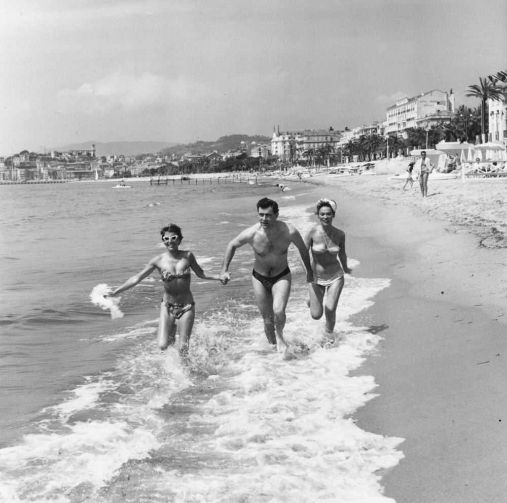 George Baker Runs Through The Surf At Cannes With Bella Darvi, 1956.