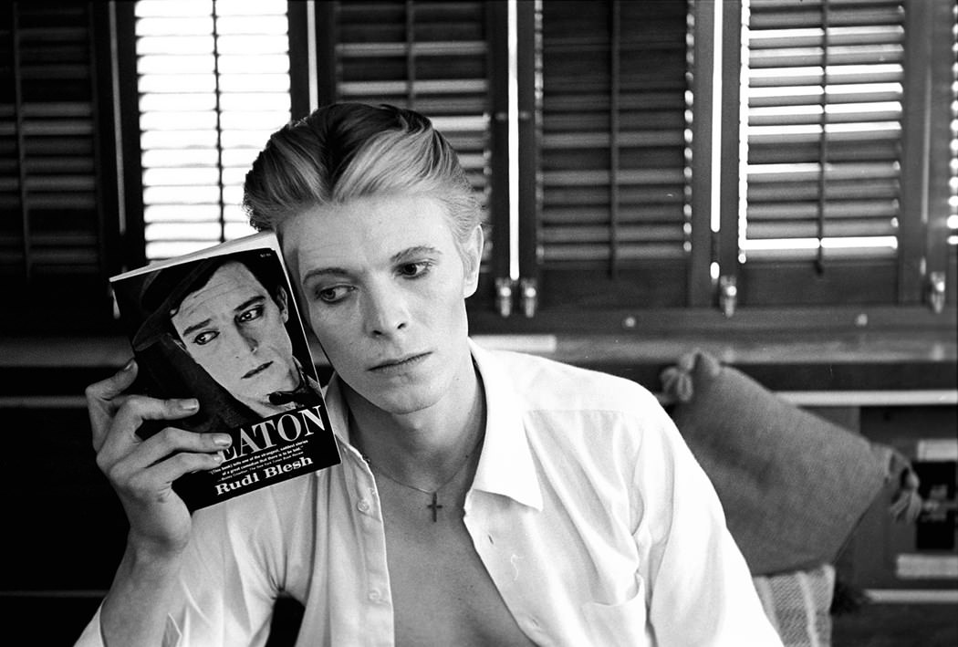 Bowie Holding A Buster Keaton Book Near His Face, In His Dressing Room Trailer On The Man Who Fell To Earth, New Mexico, 1975.