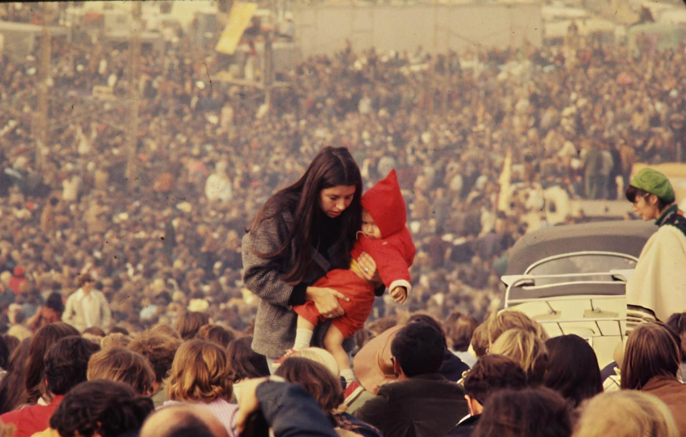 A Woman Carrying A Child Through The Crowd At The Altamont Free Concert, 1969.