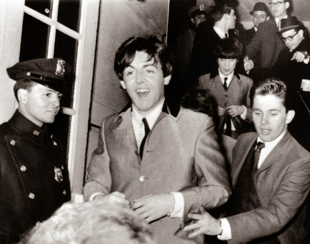 Paul Mccartney Flashes A Smile As He Rushes From New York'S Carnegie Hall After Two Wild Performances, February 12, 1964; John Lennon Is Behind Him.