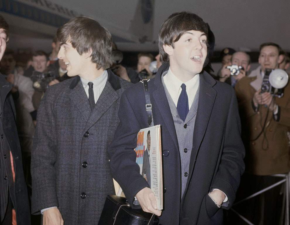 The Beatles Arrive At London Airport, England, After Their Visit To The United States, February 22, 1964; Paul Mccartney Is Carrying Record Albums, And George Harrison Is Talking To John Lennon.