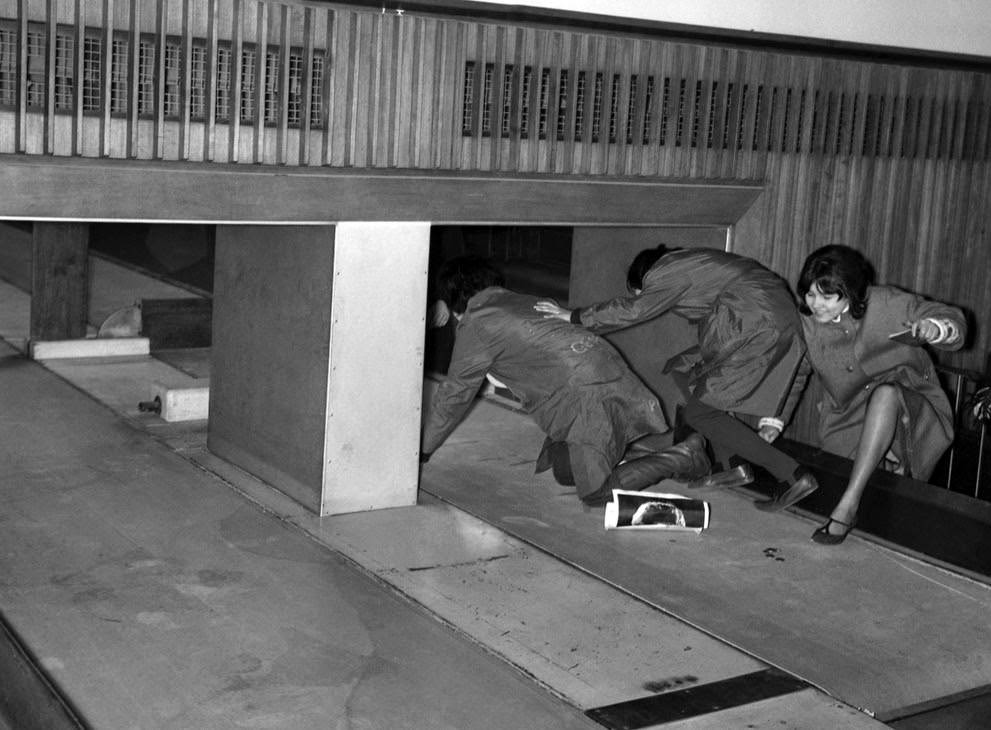 Three Beatles Fans Attempt To Enter The Customs Hall At London Airport By Crawling Into The Baggage Conveyor Belt, February 5, 1964.