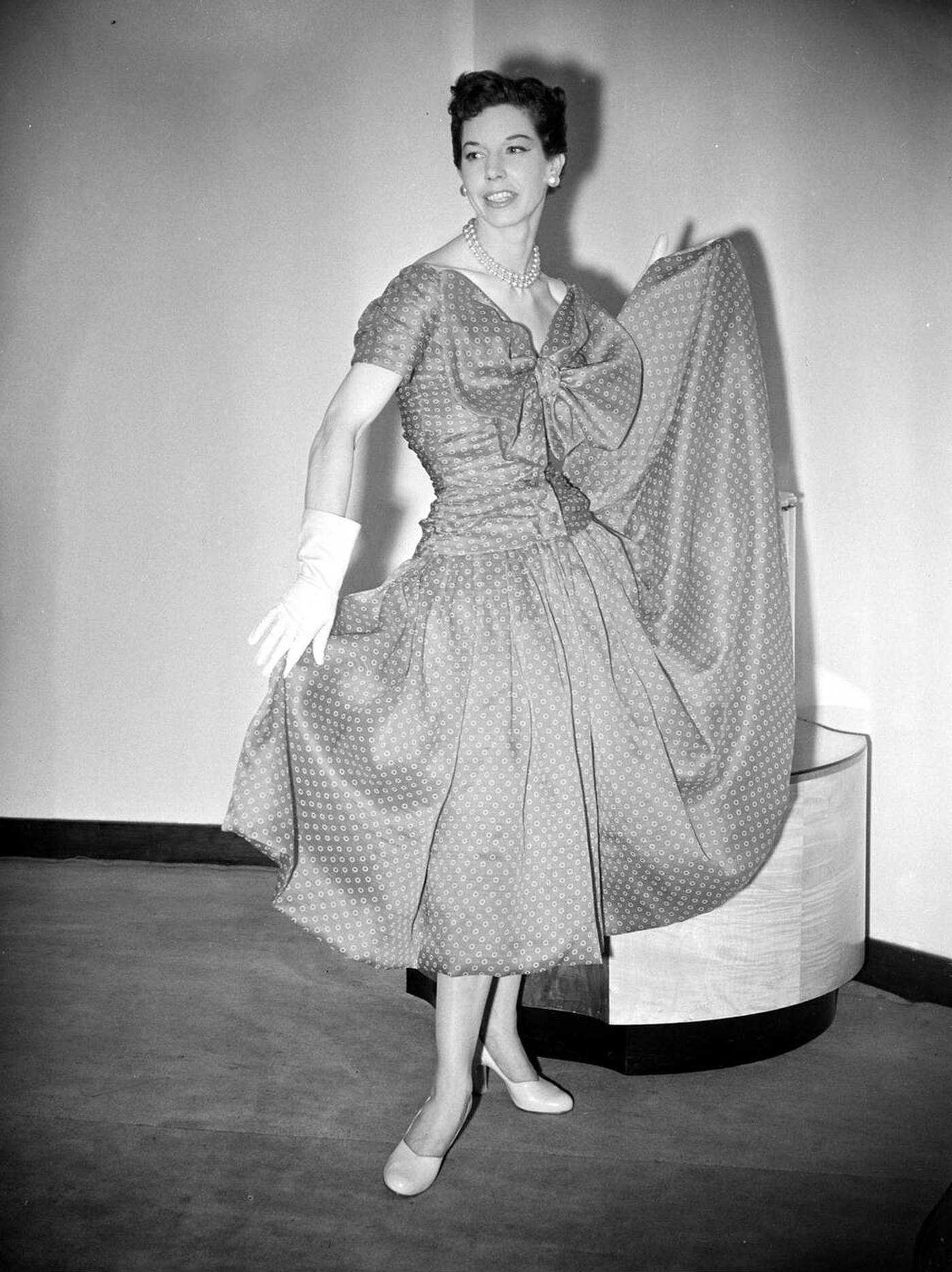 Model Dorothy Emms Displays Harmony A Red Printed Organza Dress With Large Bow At The Bodice And An Extra Full Skirt, One Of The Christian Dior Dresses Which Are Being Made In England, 1952.